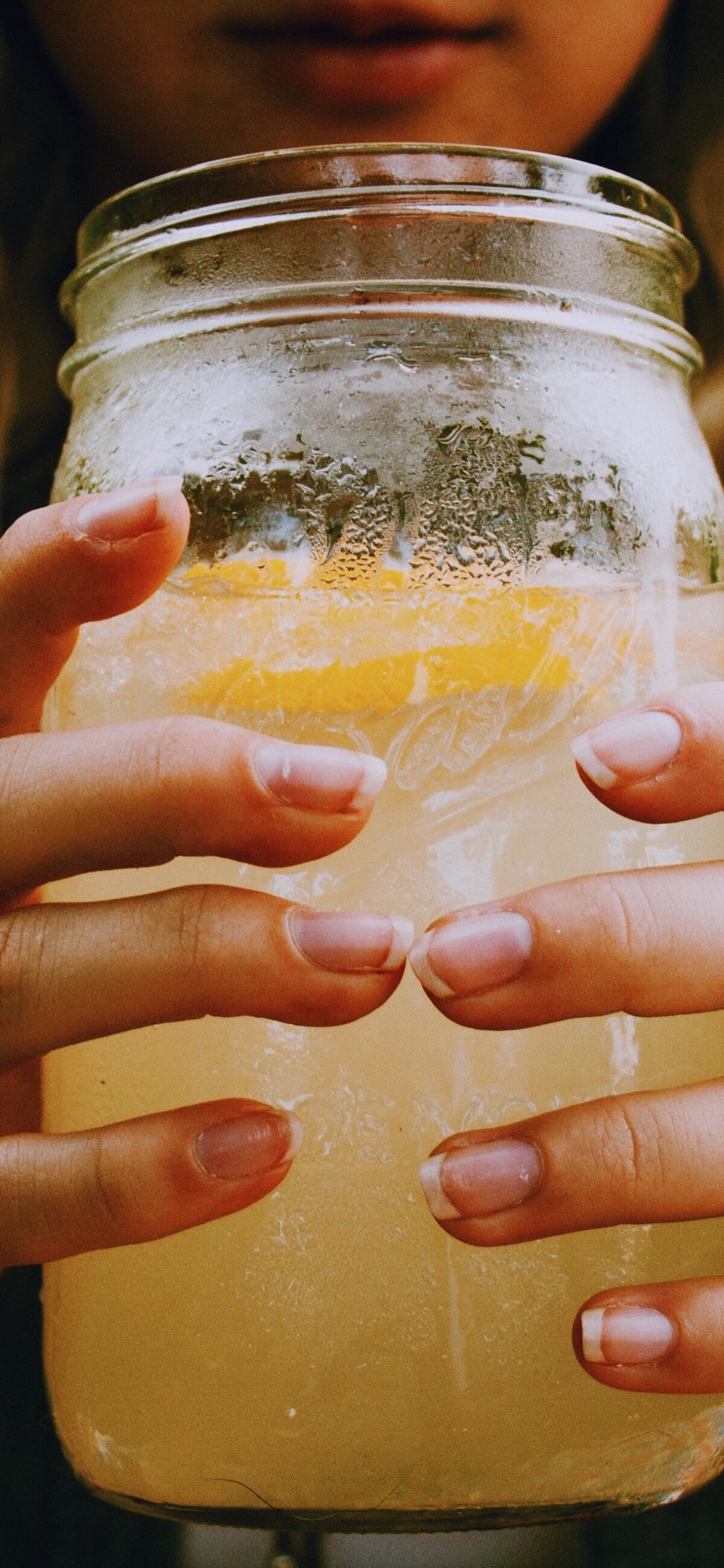 Woman Holding Clear Glass Jar With Yellow Liquid. Wallpaper in 1242x2688 Resolution
