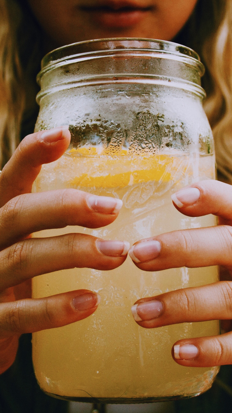 Woman Holding Clear Glass Jar With Yellow Liquid. Wallpaper in 750x1334 Resolution