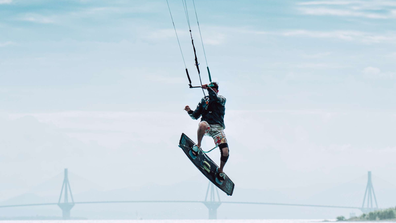 Man in Black Jacket and Black Pants Riding on Black Snowboard Under White Clouds and Blue. Wallpaper in 1280x720 Resolution