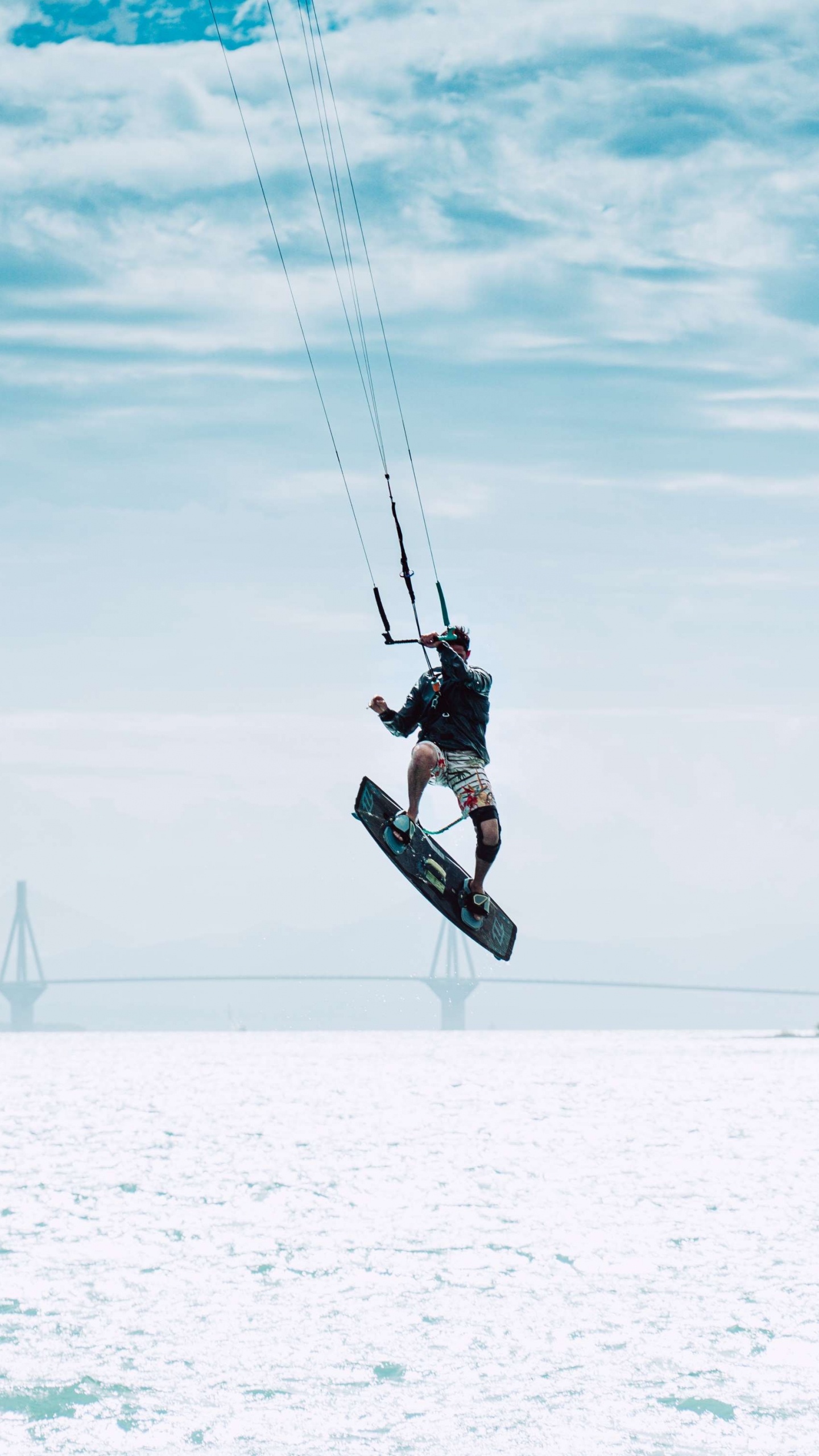 Man in Black Jacket and Black Pants Riding on Black Snowboard Under White Clouds and Blue. Wallpaper in 1440x2560 Resolution