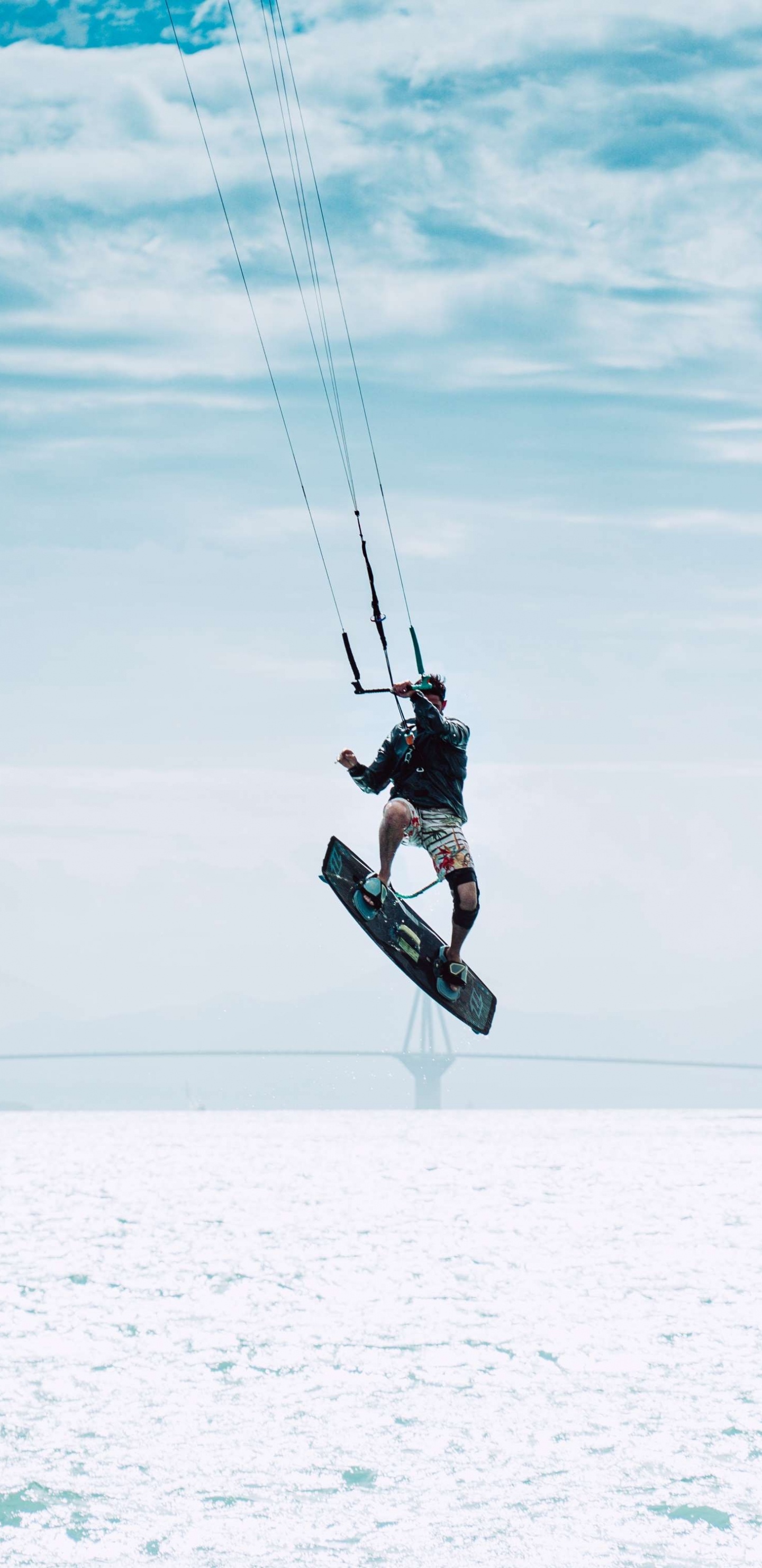 Man in Black Jacket and Black Pants Riding on Black Snowboard Under White Clouds and Blue. Wallpaper in 1440x2960 Resolution