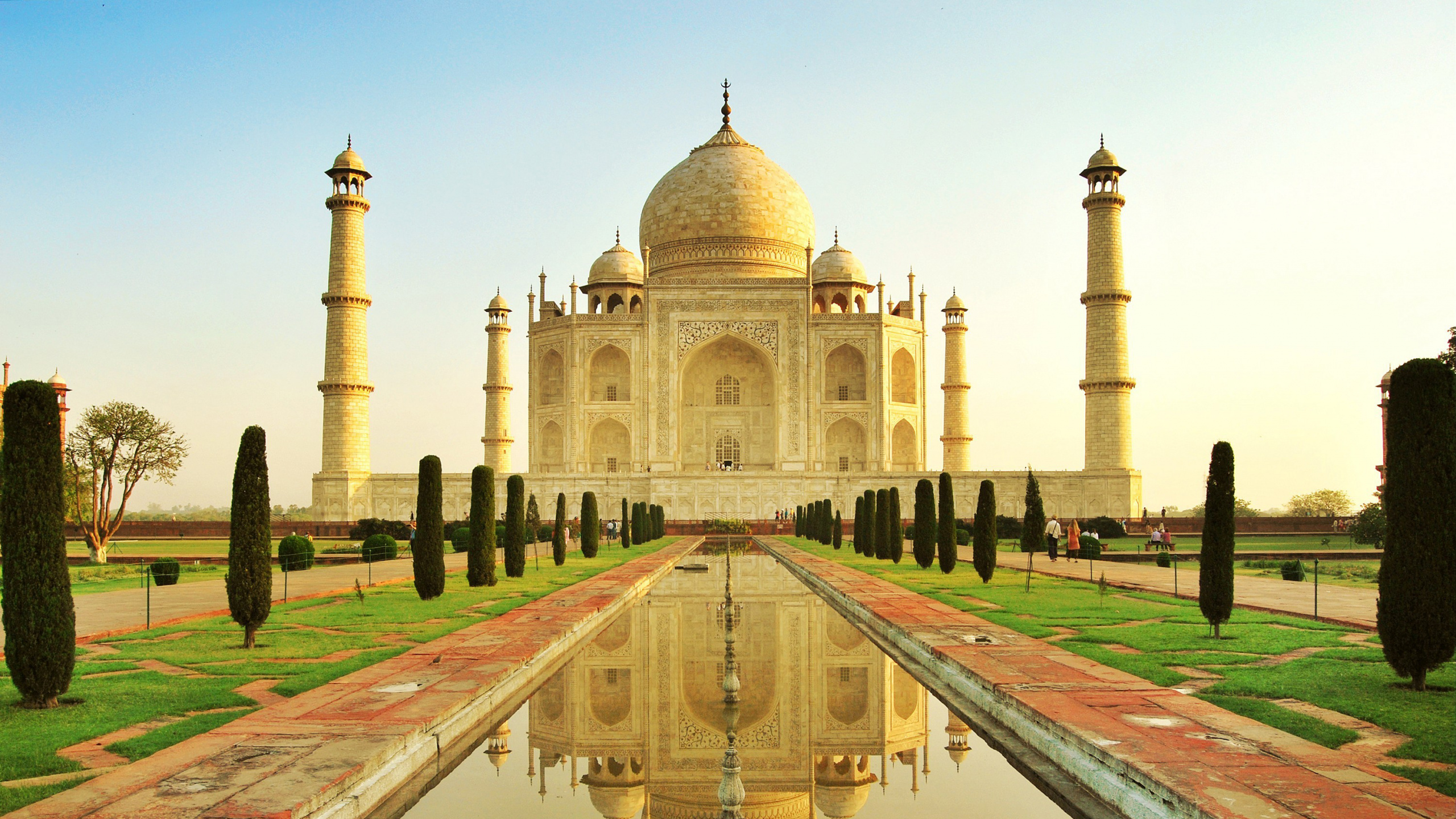 Leute, Die Tagsüber Auf Einem Park in Der Nähe Eines Weißen Betongebäudes Spazieren Gehen. Wallpaper in 2560x1440 Resolution