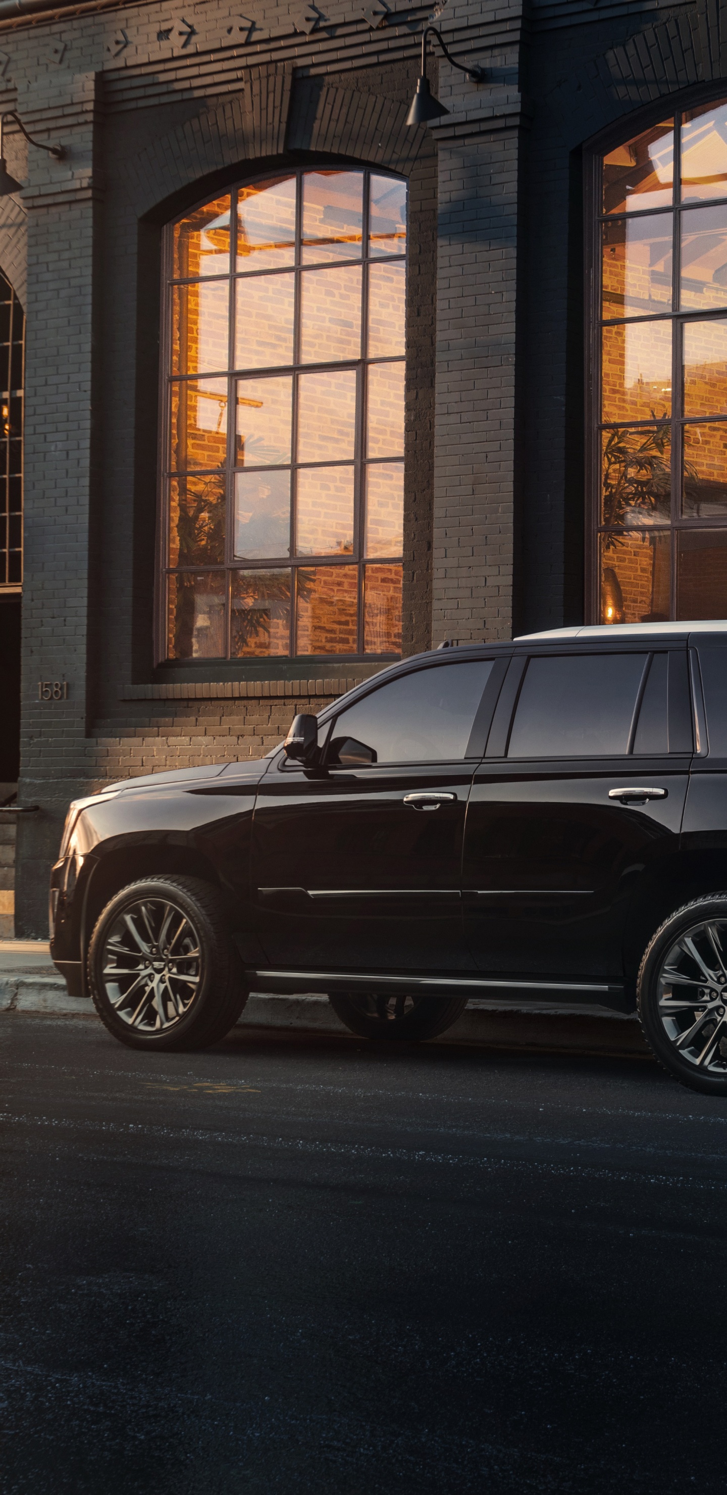 Black Suv Parked in Front of Brown Building. Wallpaper in 1440x2960 Resolution