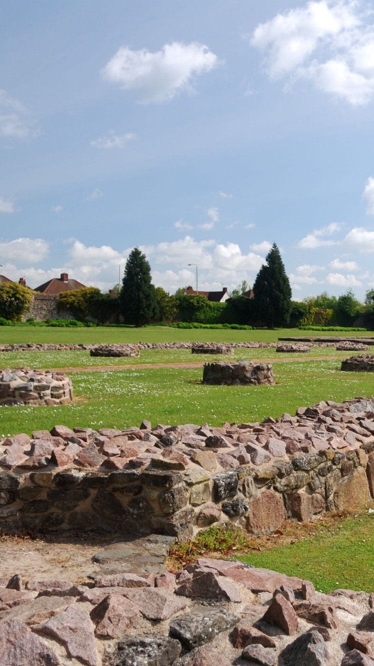 Campo de Hierba Verde Con Rocas y Árboles Bajo un Cielo Azul Durante el Día. Wallpaper in 750x1334 Resolution