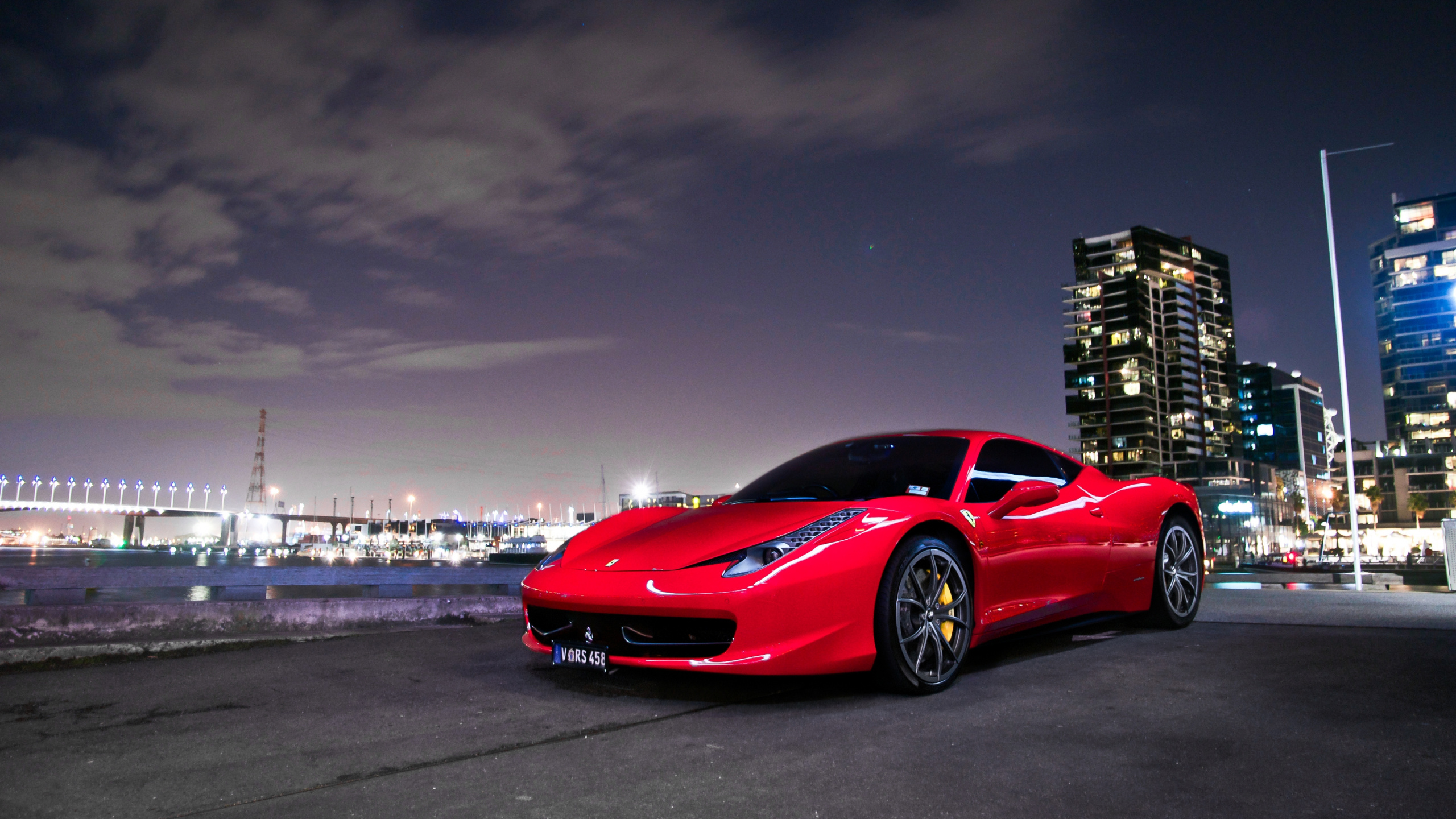 Ferrari 458 Italia Rojo en la Carretera Cerca de Los Edificios de la Ciudad Durante la Noche. Wallpaper in 2560x1440 Resolution