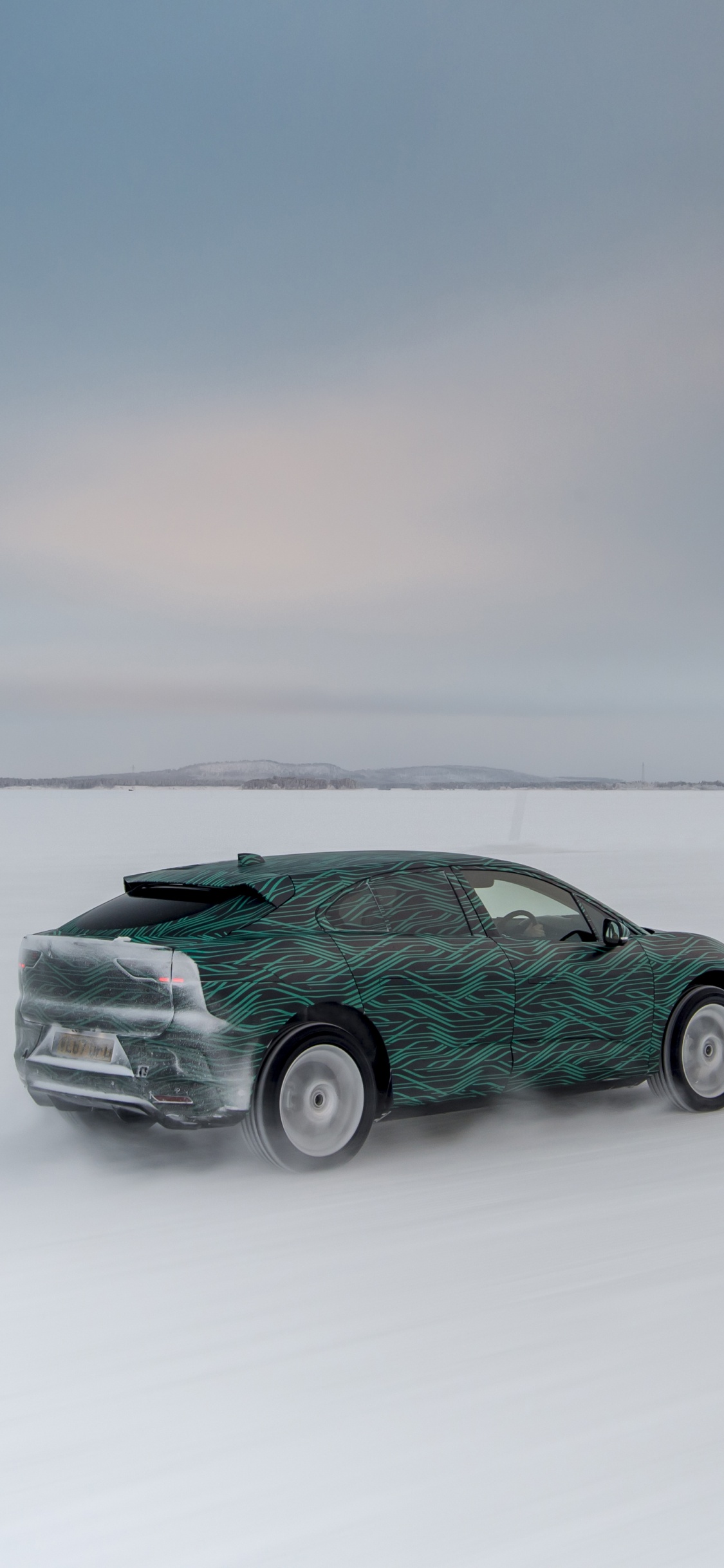 Green Car on Snow Covered Field. Wallpaper in 1125x2436 Resolution