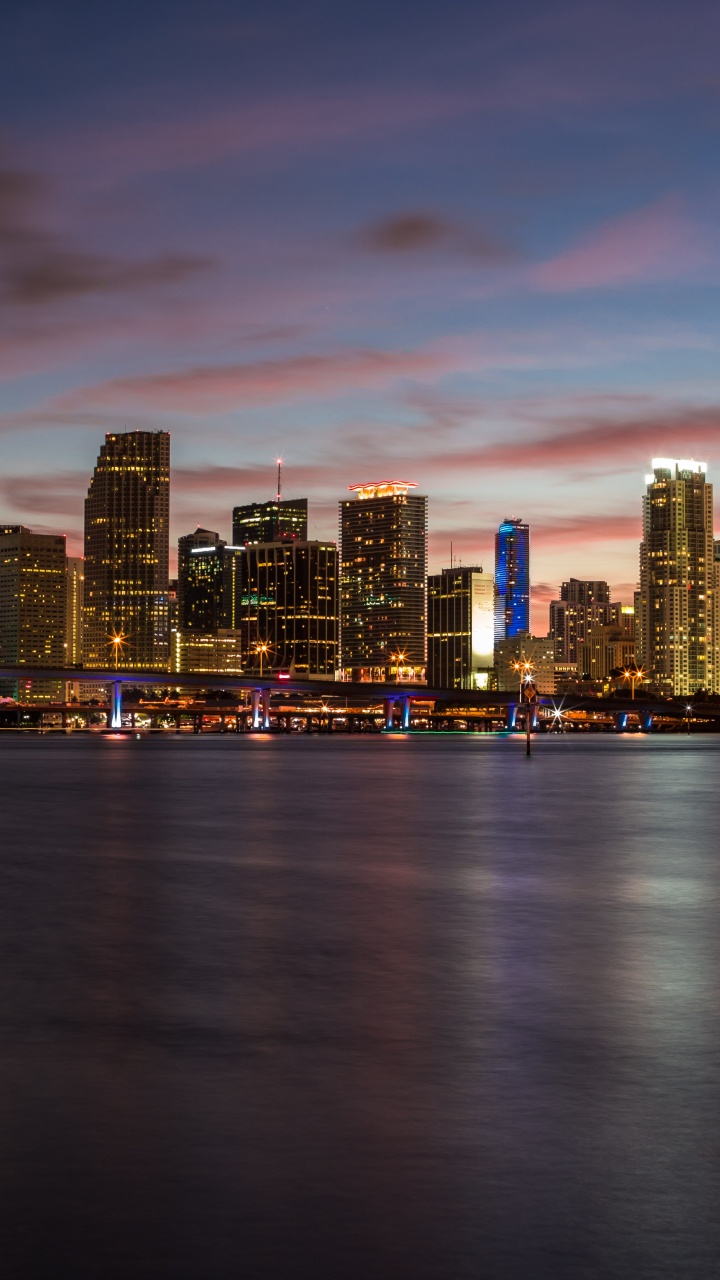 Skyline Der Stadt Über Gewässer Bei Sonnenuntergang. Wallpaper in 720x1280 Resolution