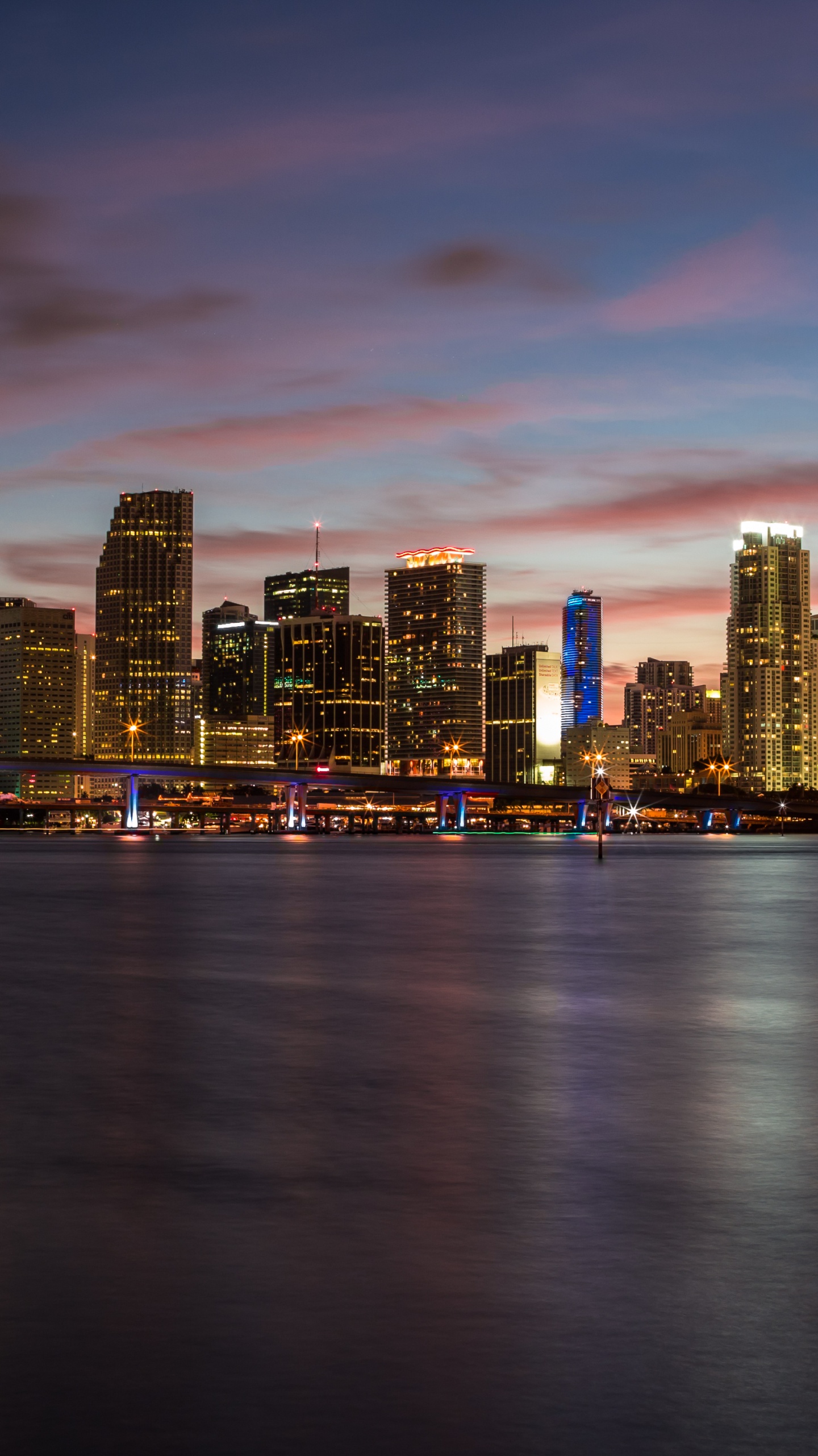 City Skyline Across Body of Water During Sunset. Wallpaper in 1440x2560 Resolution