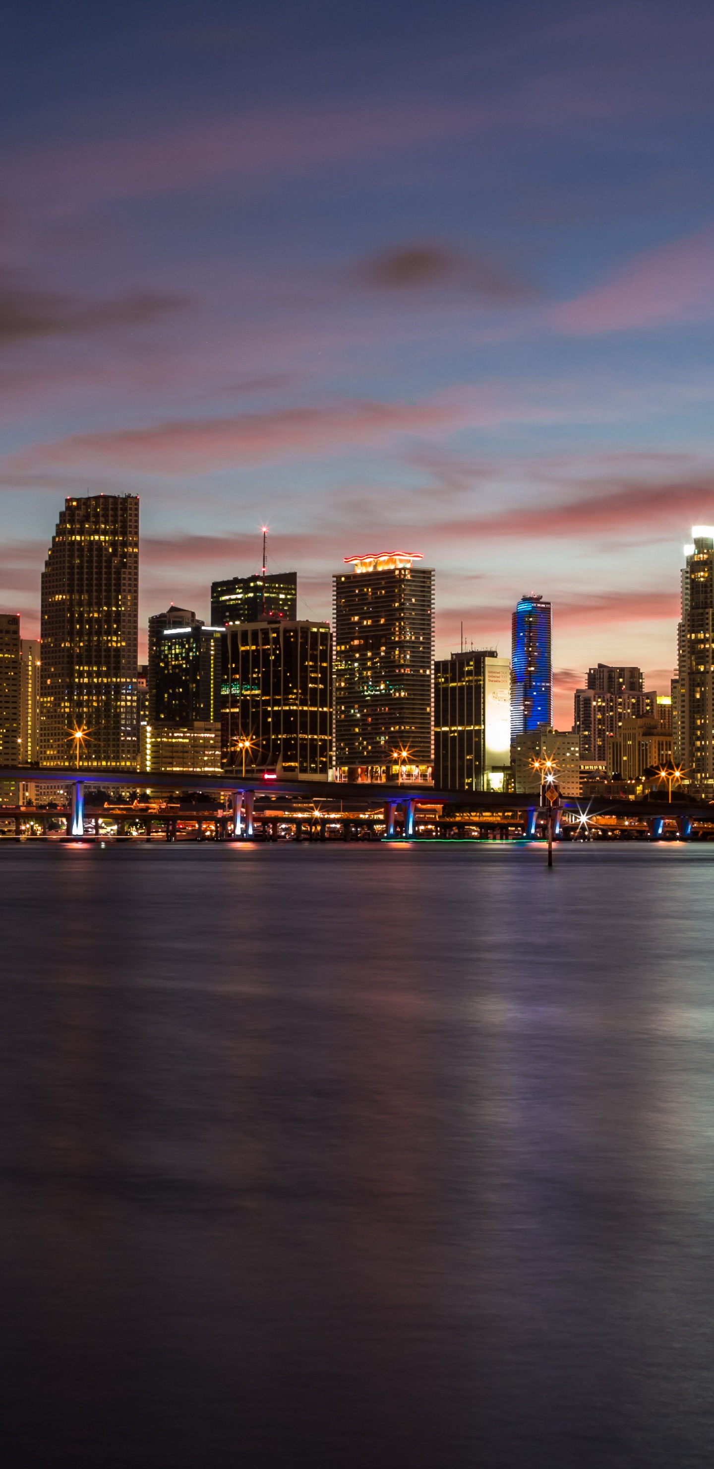 City Skyline Across Body of Water During Sunset. Wallpaper in 1440x2960 Resolution