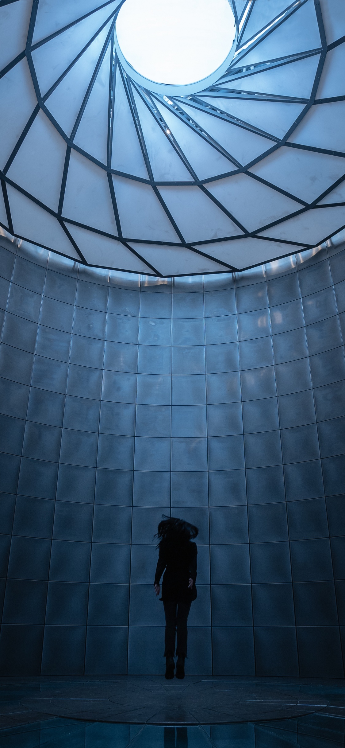 Mann in Schwarzer Jacke Steht Vor Glaswand. Wallpaper in 1125x2436 Resolution