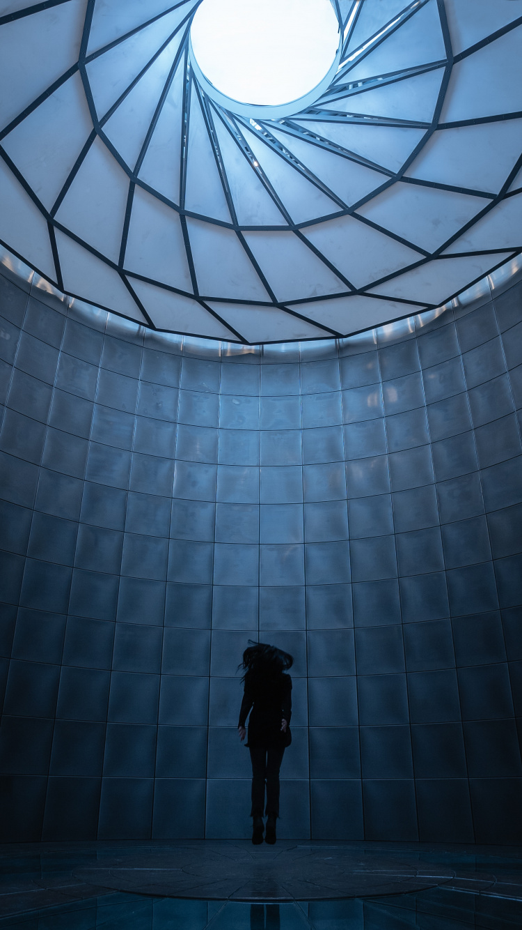 Mann in Schwarzer Jacke Steht Vor Glaswand. Wallpaper in 750x1334 Resolution