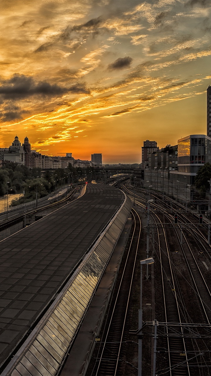 Tren Ferroviario Cerca de Los Edificios de la Ciudad Durante la Puesta de Sol. Wallpaper in 720x1280 Resolution