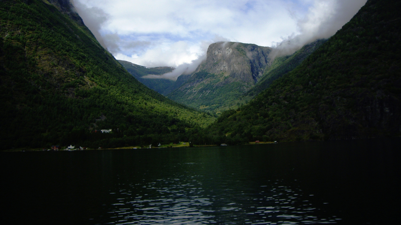 Montañas Verdes Junto al Cuerpo de Agua Bajo un Cielo Nublado Durante el Día. Wallpaper in 1366x768 Resolution