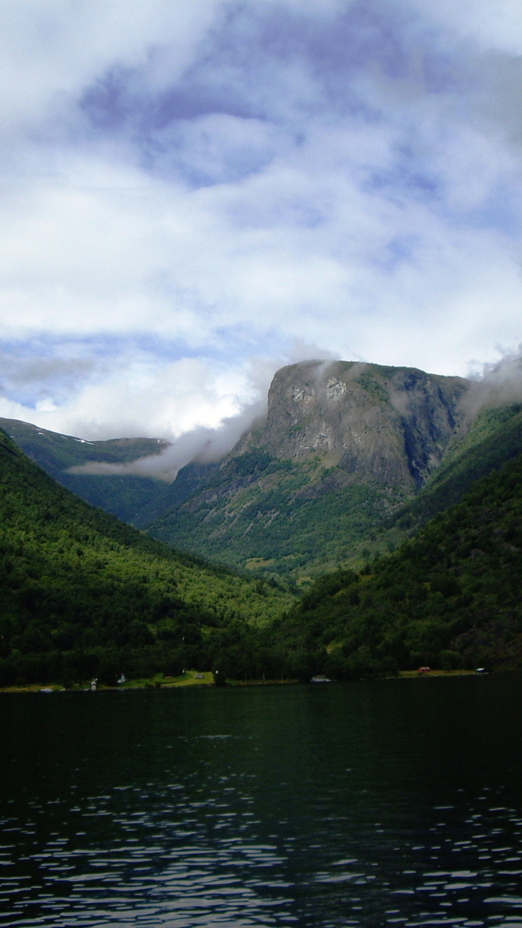 Green Mountains Beside Body of Water Under Cloudy Sky During Daytime. Wallpaper in 750x1334 Resolution