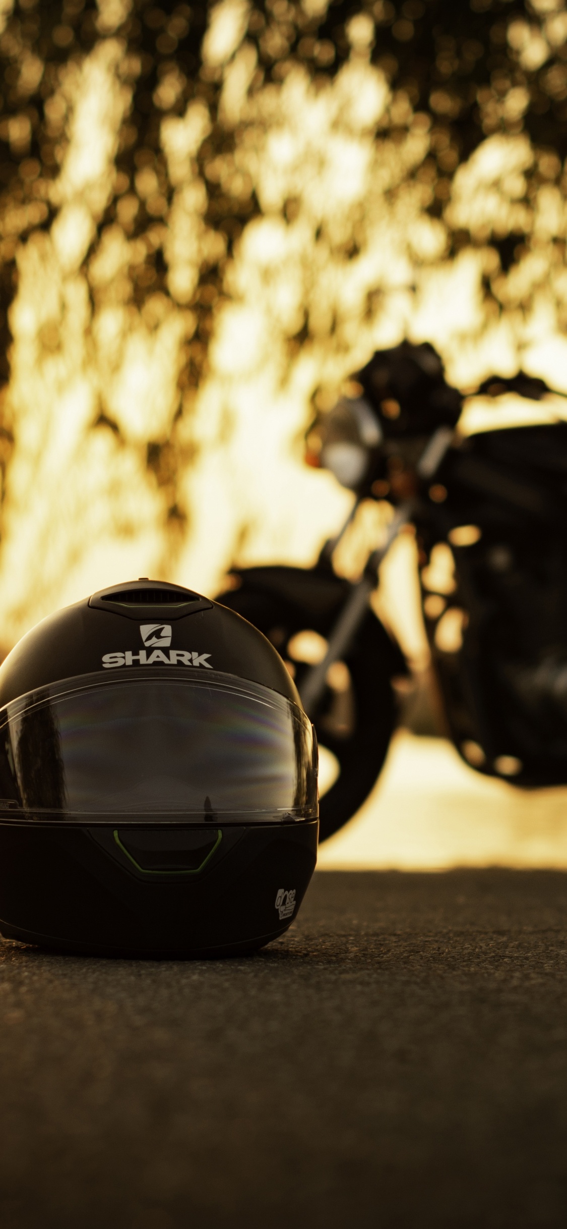 Schwarzes Motorrad Tagsüber Auf Der Straße Geparkt. Wallpaper in 1125x2436 Resolution