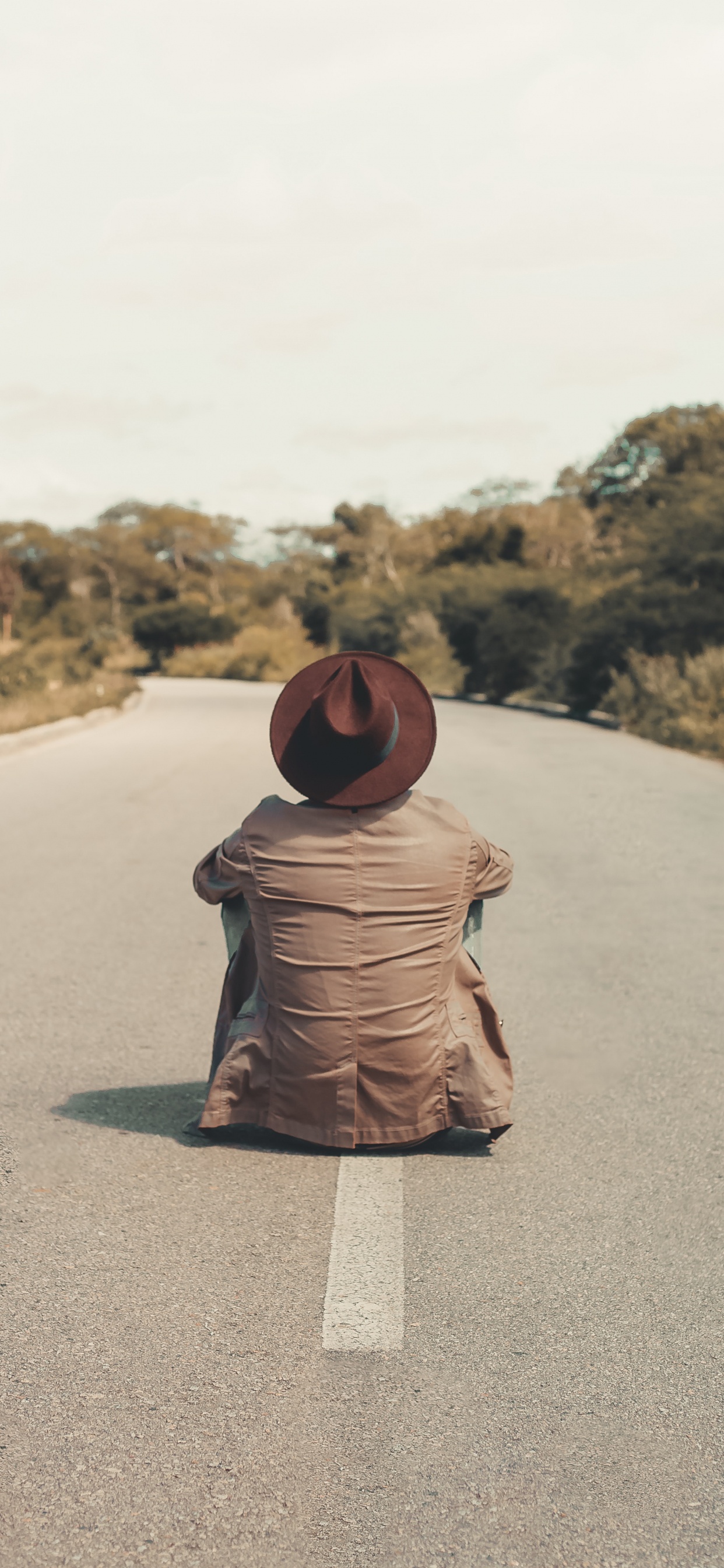 Woman in Brown Hijab Sitting on Gray Asphalt Road During Daytime. Wallpaper in 1242x2688 Resolution
