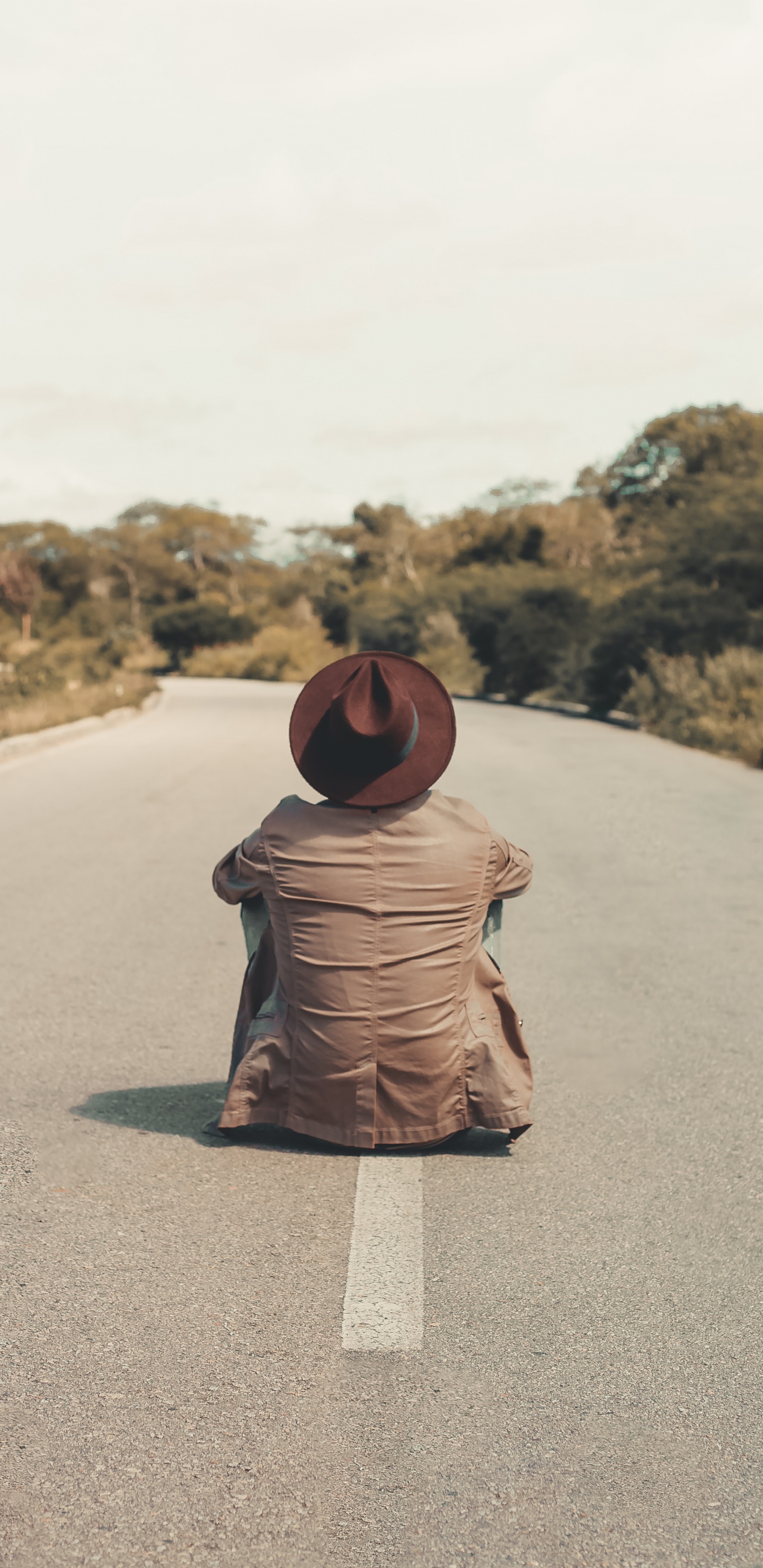 Woman in Brown Hijab Sitting on Gray Asphalt Road During Daytime. Wallpaper in 1440x2960 Resolution
