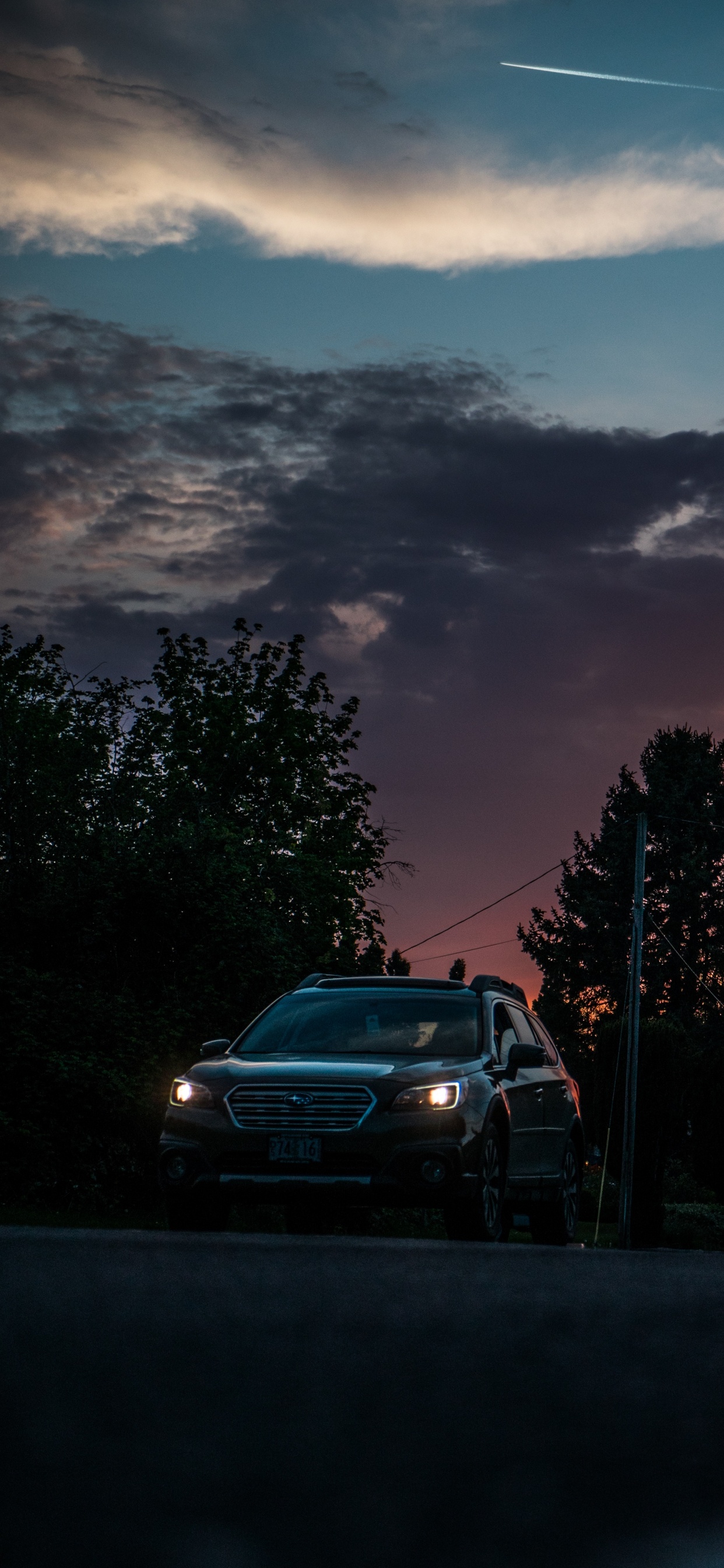 Graues Auto Auf Der Straße in Der Nähe Von Bäumen Bei Sonnenuntergang. Wallpaper in 1242x2688 Resolution