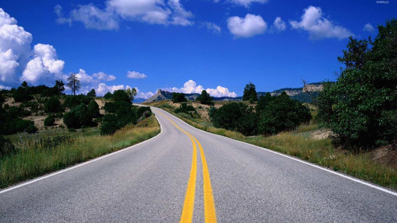 Gray Concrete Road Between Green Grass Field Under Blue Sky and White Clouds During Daytime. Wallpaper in 1366x768 Resolution