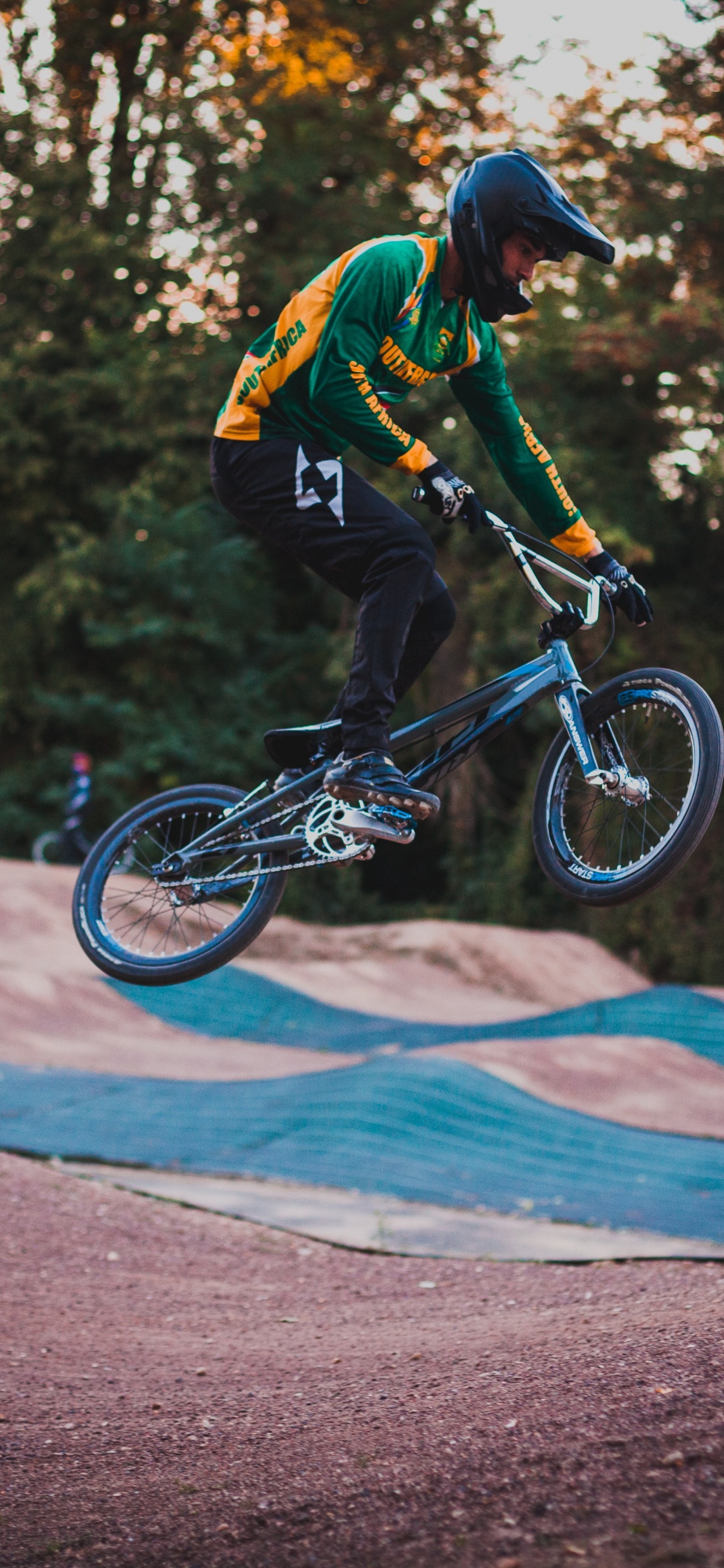 Homme en Veste Noire et Orange à Cheval Sur un Vélo Noir et Blanc Sur Route Pendant la Journée. Wallpaper in 1125x2436 Resolution