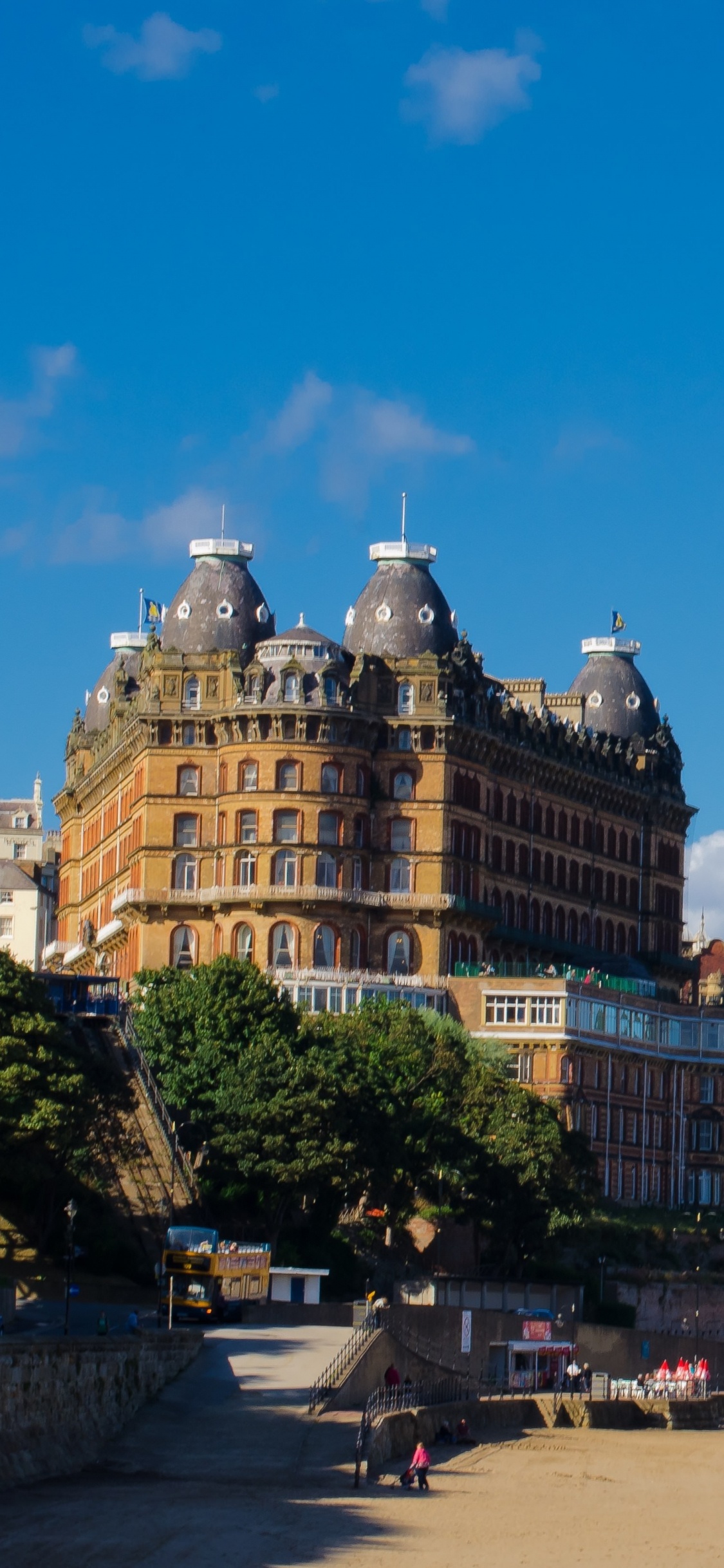 Personnes Marchant Dans la Rue Près D'un Bâtiment en Béton Brun Sous un Ciel Bleu Pendant la Journée. Wallpaper in 1125x2436 Resolution