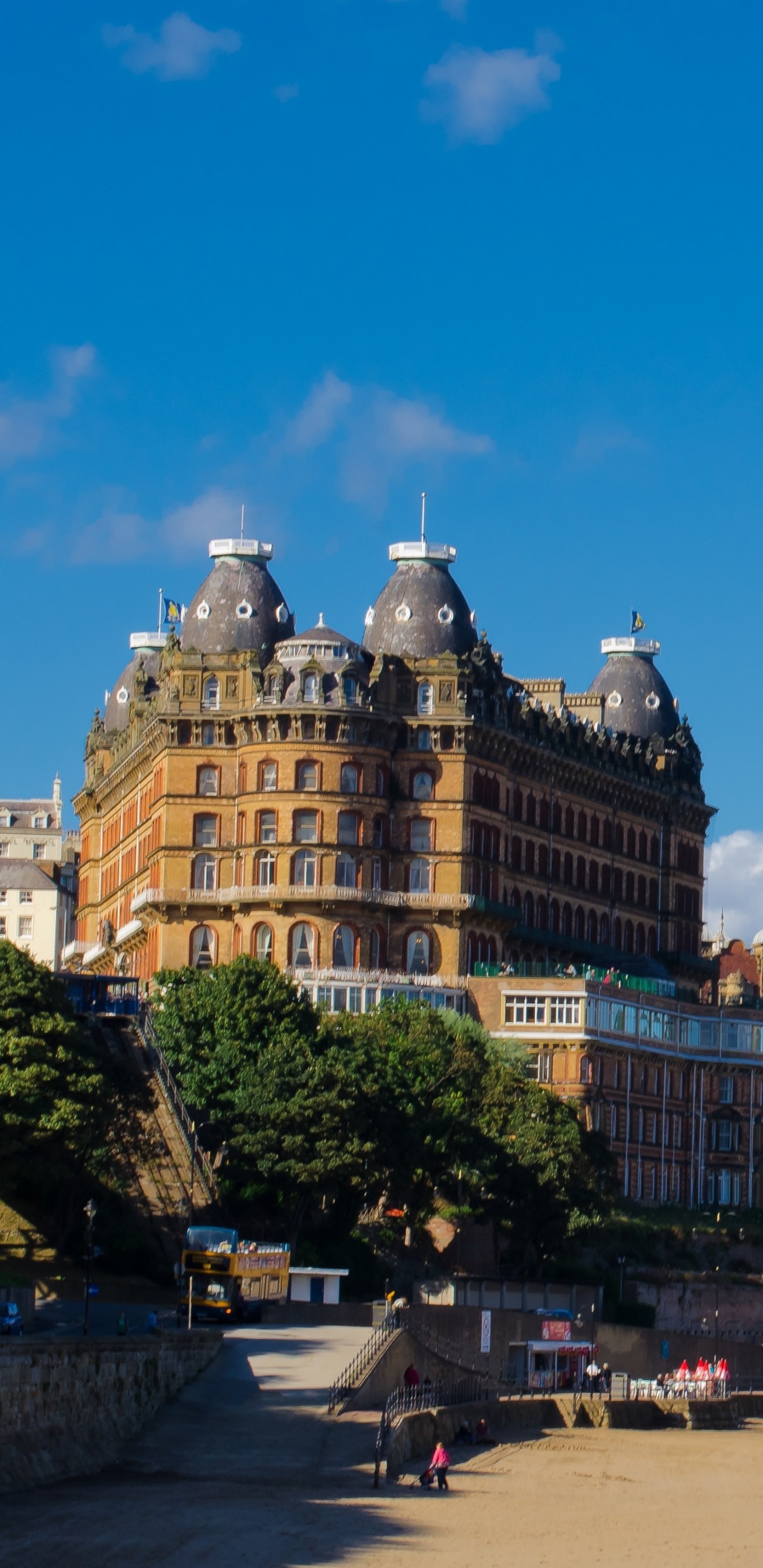 Personnes Marchant Dans la Rue Près D'un Bâtiment en Béton Brun Sous un Ciel Bleu Pendant la Journée. Wallpaper in 1440x2960 Resolution