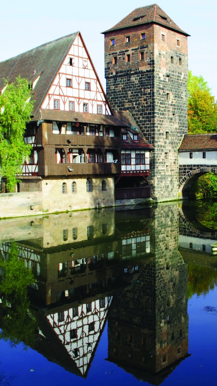 Braunes Backsteingebäude am Fluss Tagsüber. Wallpaper in 720x1280 Resolution