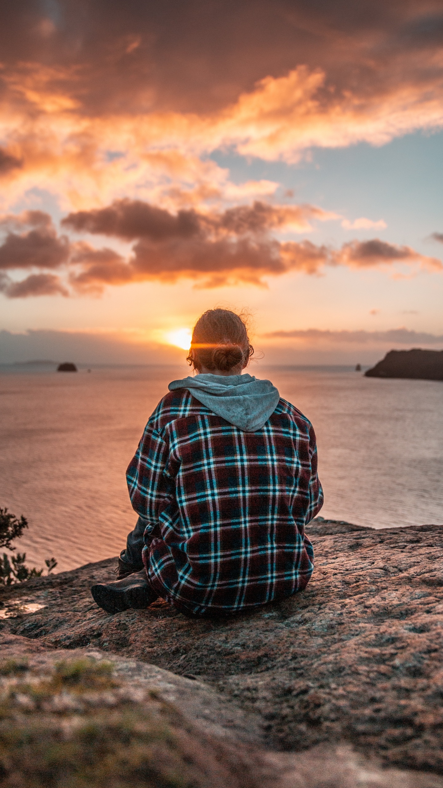 Man in Blue and White Plaid Dress Shirt Sitting on Rock Near Body of Water During. Wallpaper in 1440x2560 Resolution