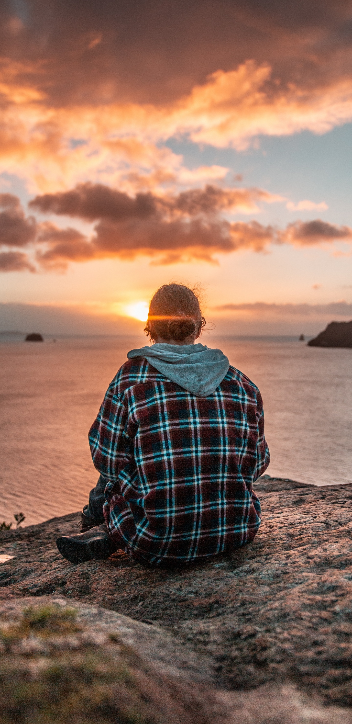 Man in Blue and White Plaid Dress Shirt Sitting on Rock Near Body of Water During. Wallpaper in 1440x2960 Resolution