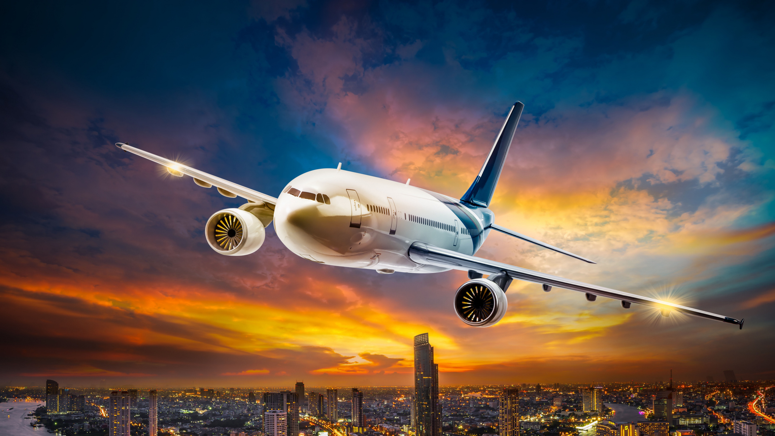 White Passenger Plane Flying Over City Buildings During Daytime. Wallpaper in 2560x1440 Resolution