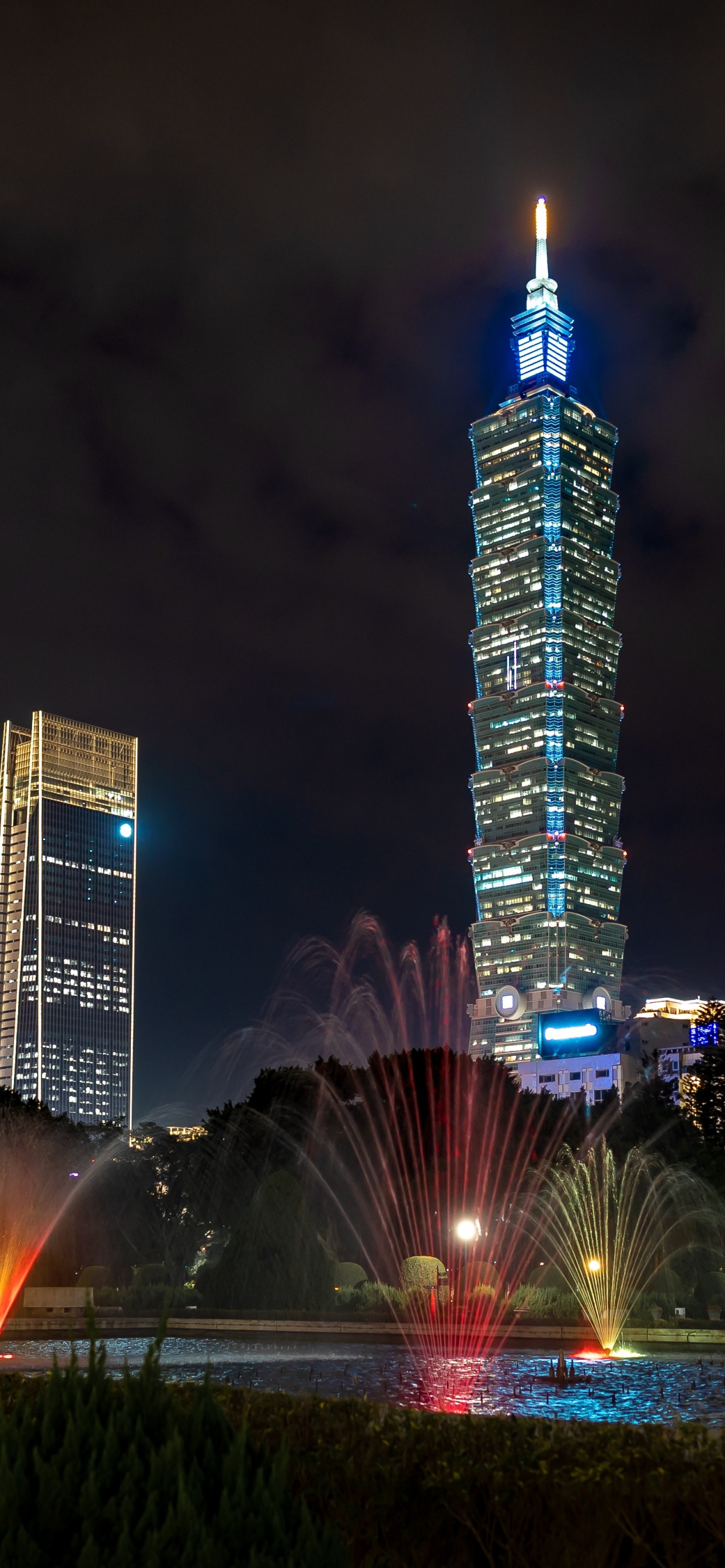 Edificio Alto Iluminado Durante la Noche.. Wallpaper in 1242x2688 Resolution