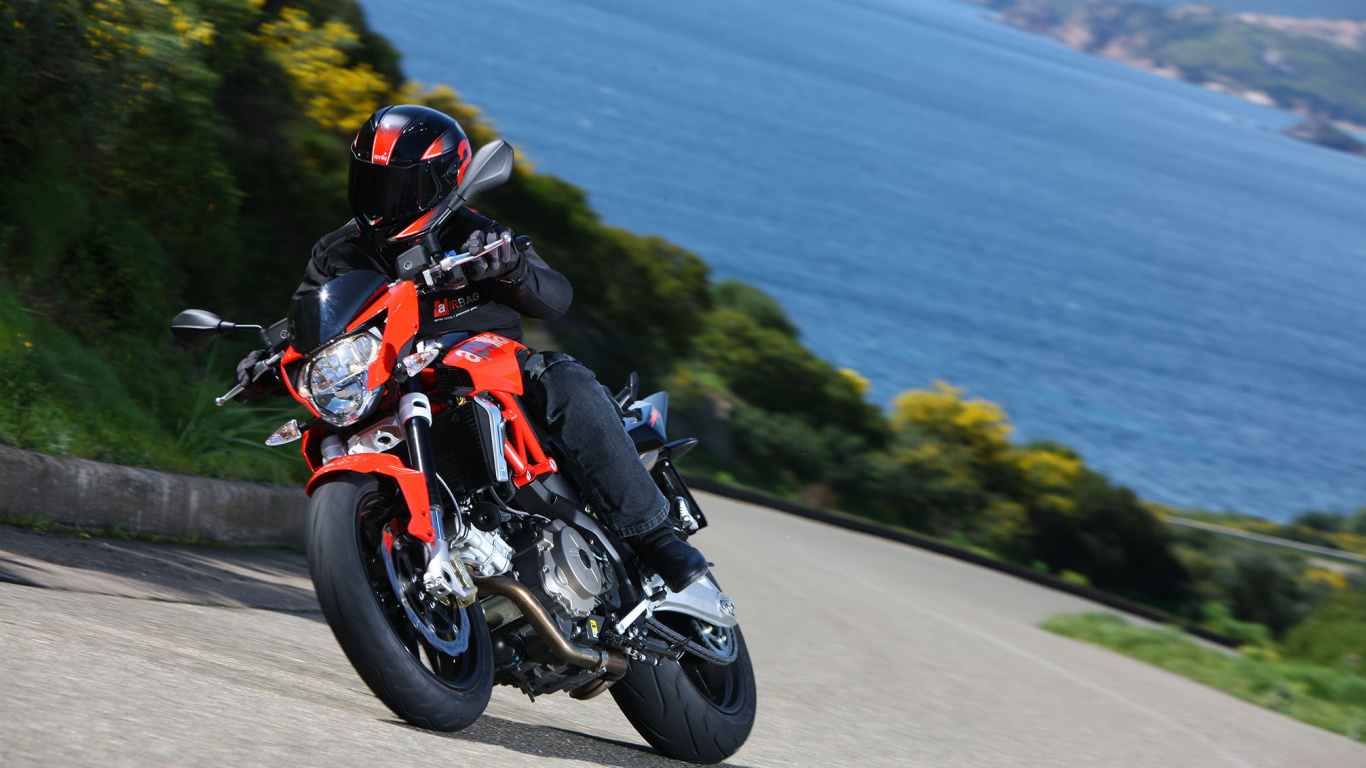 Homme en Costume de Moto Orange et Noir Équitation Sur Moto Sur Route Pendant la Journée. Wallpaper in 1366x768 Resolution