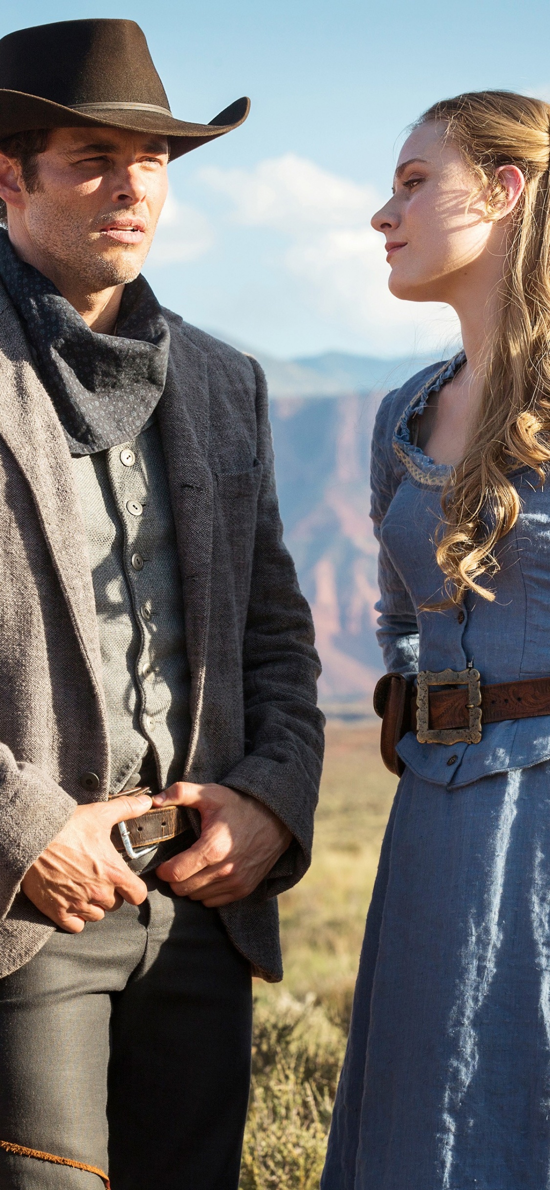 Woman in Blue Dress Standing Beside Man in Brown Jacket. Wallpaper in 1125x2436 Resolution