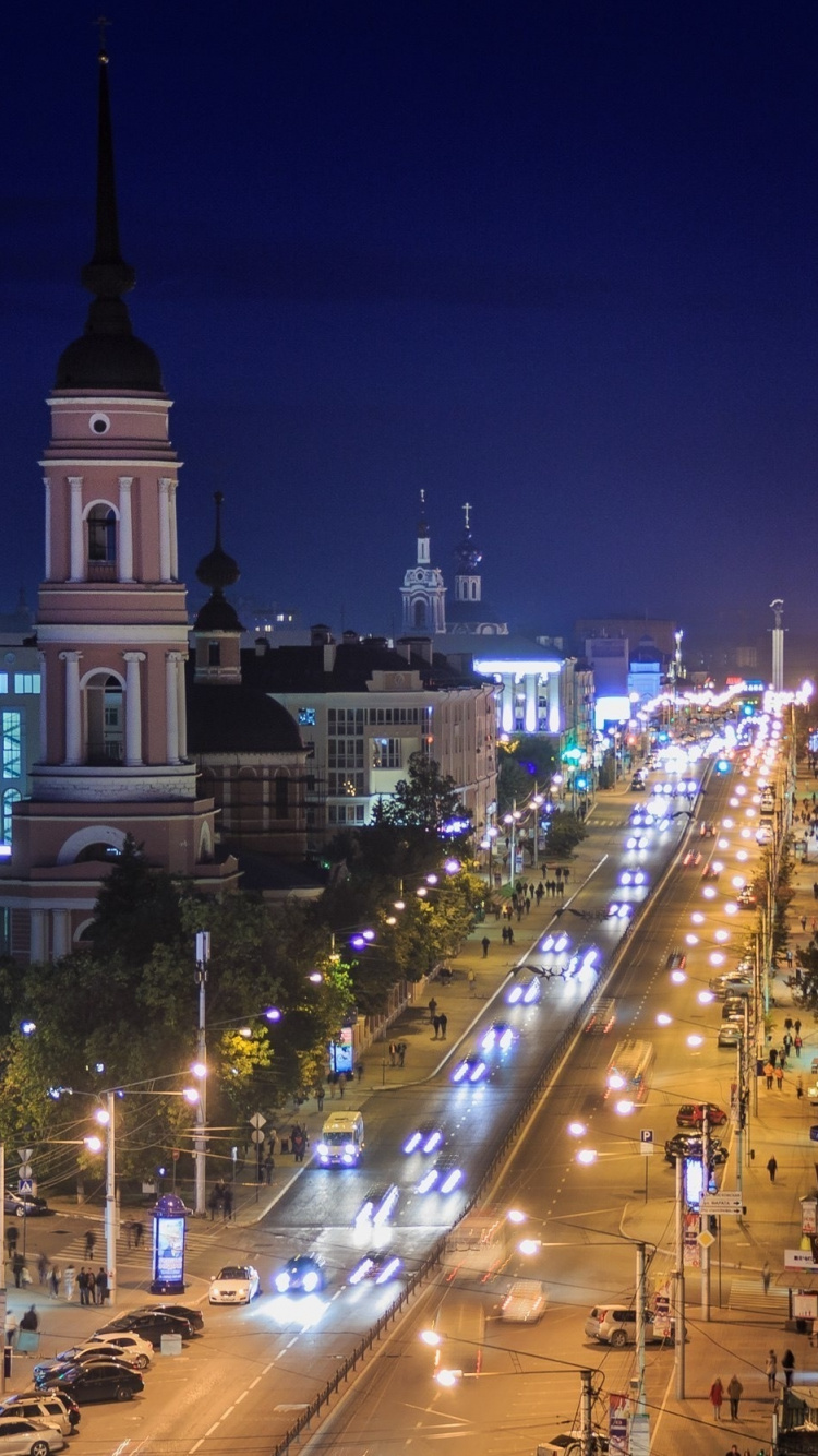 Coches en la Carretera Entre Edificios de Gran Altura Durante la Noche. Wallpaper in 750x1334 Resolution