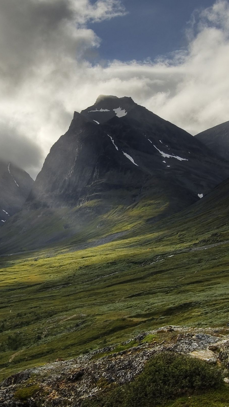 Green Grass Field Near Mountain Under Cloudy Sky During Daytime. Wallpaper in 750x1334 Resolution