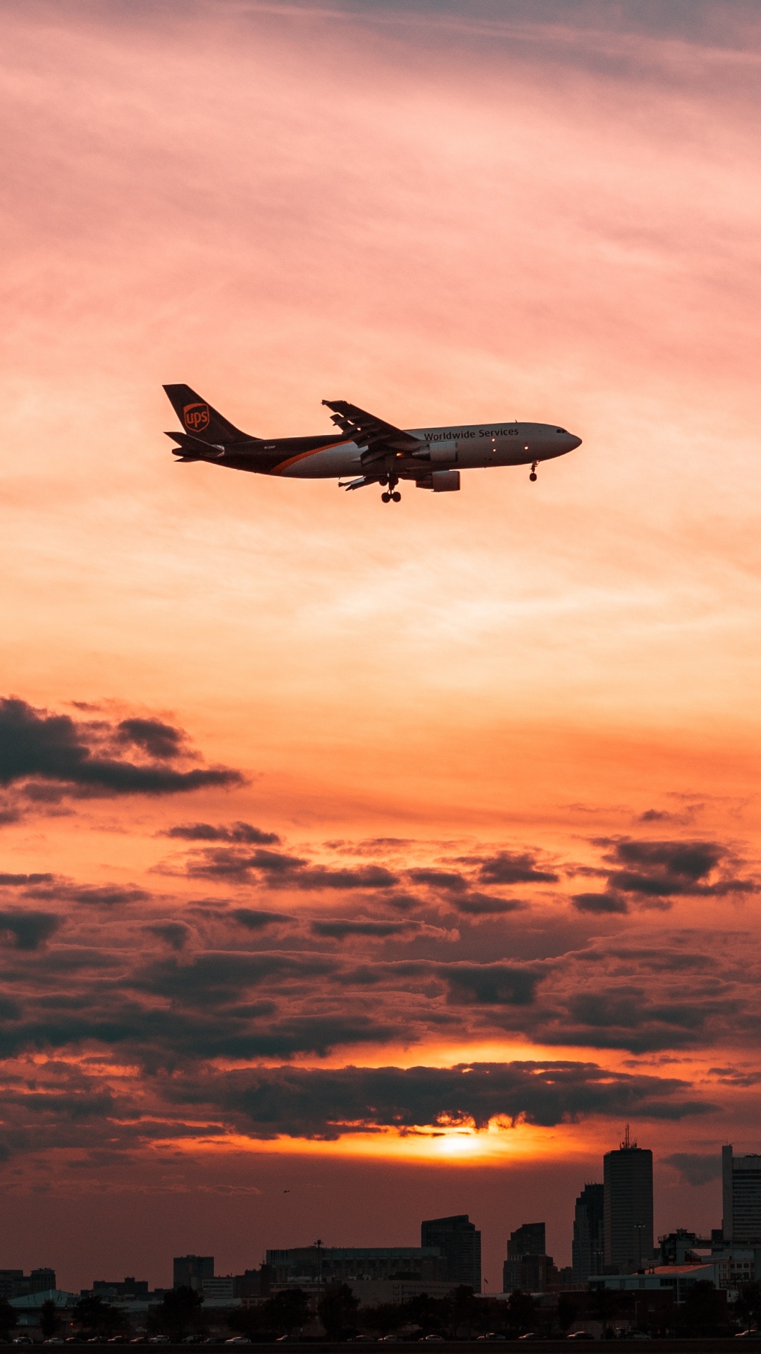 Weißes Flugzeug, Das Während Des Sonnenuntergangs Über Die Stadt Fliegt. Wallpaper in 1080x1920 Resolution