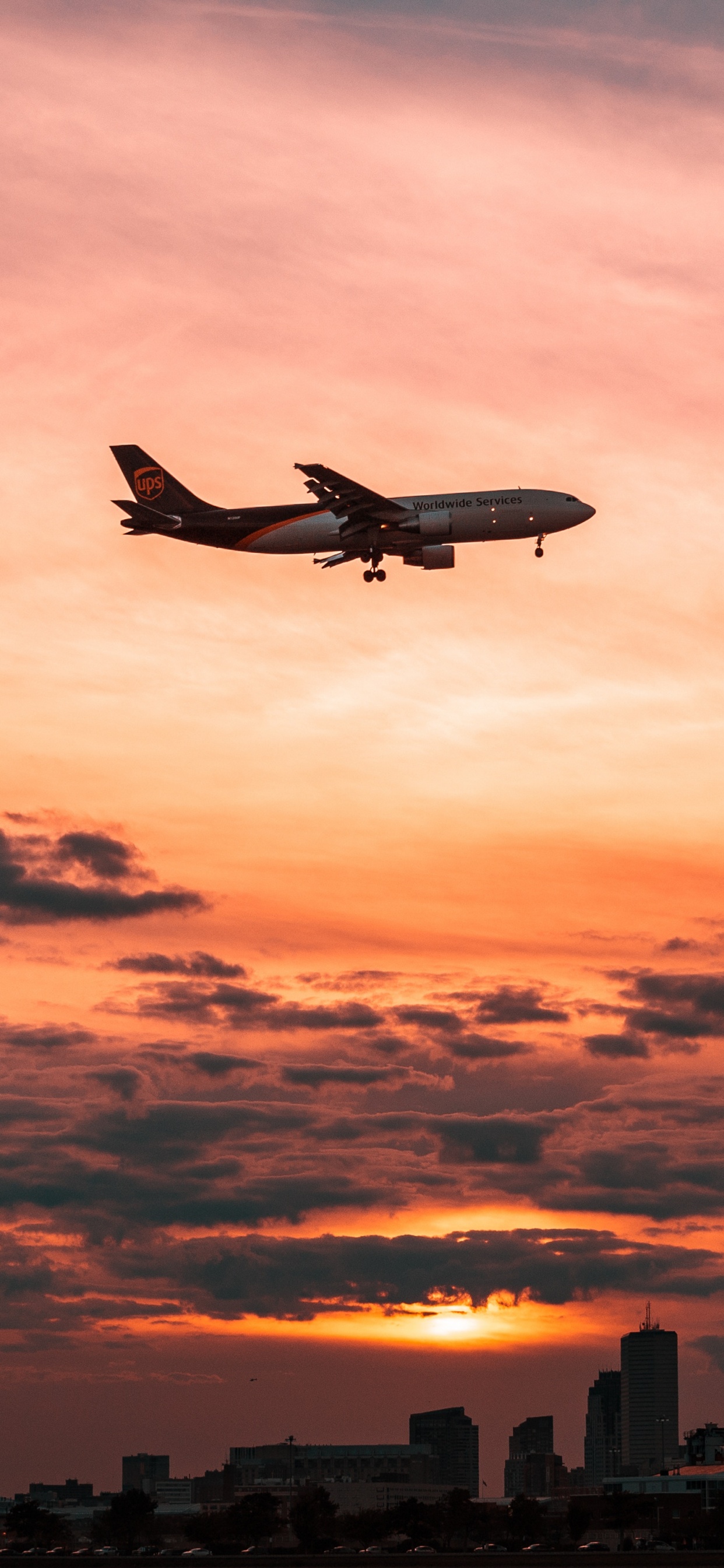 Weißes Flugzeug, Das Während Des Sonnenuntergangs Über Die Stadt Fliegt. Wallpaper in 1242x2688 Resolution