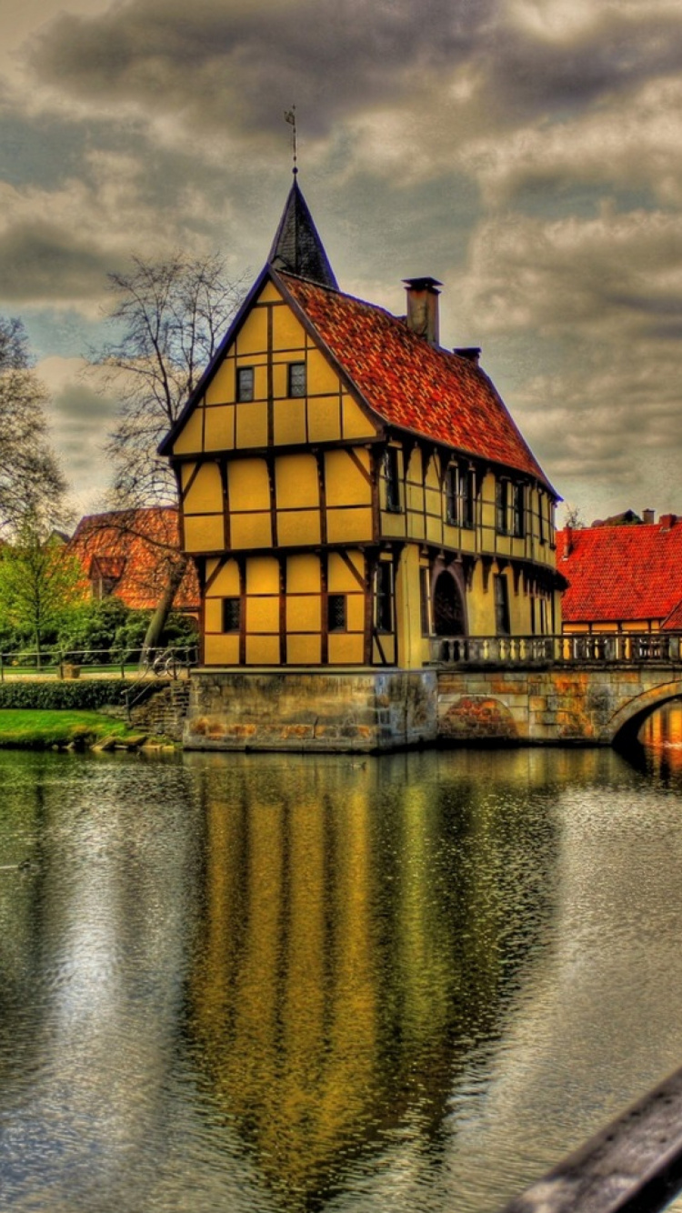 Bâtiment en Béton Rouge et Jaune à Côté de la Rivière Sous un Ciel Nuageux Pendant la Journée. Wallpaper in 750x1334 Resolution