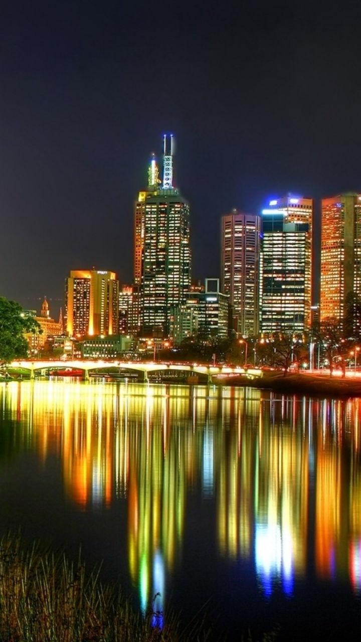 Body of Water Near Green Trees and High Rise Buildings During Night Time. Wallpaper in 720x1280 Resolution
