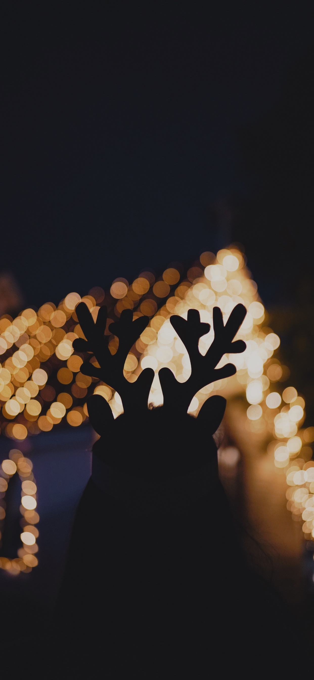 Man With Yellow String Lights on His Face. Wallpaper in 1242x2688 Resolution