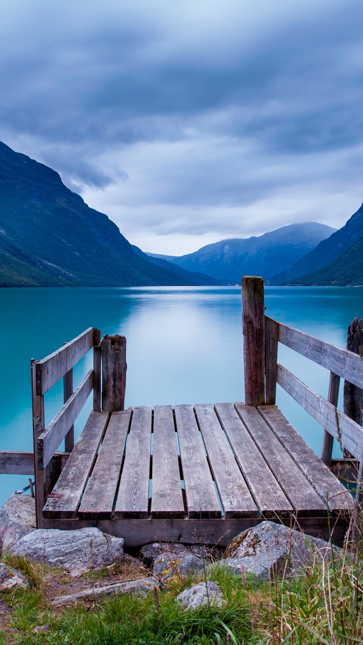 Brown Wooden Bench on Green Grass Field Near Lake and Mountains During Daytime. Wallpaper in 720x1280 Resolution