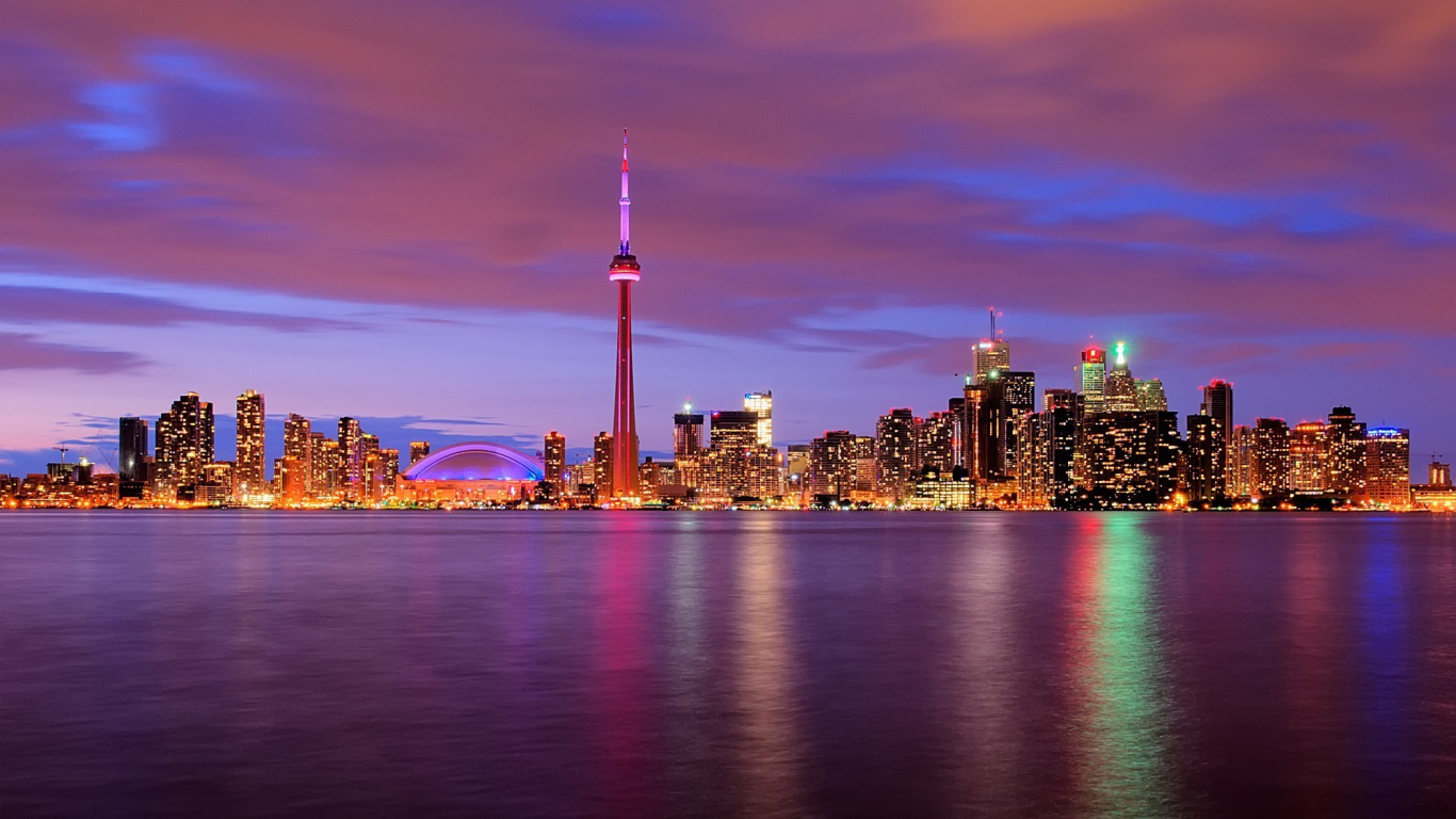 Skyline Der Stadt Über Gewässer Während Der Nacht. Wallpaper in 1366x768 Resolution