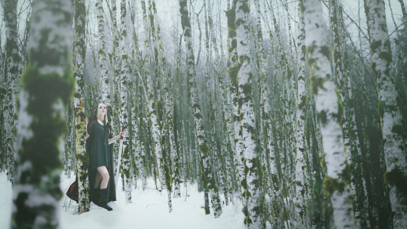 Mujer en Vestido Negro de Pie Sobre un Terreno Cubierto de Nieve Cerca de Árboles Verdes Durante el Día. Wallpaper in 1366x768 Resolution