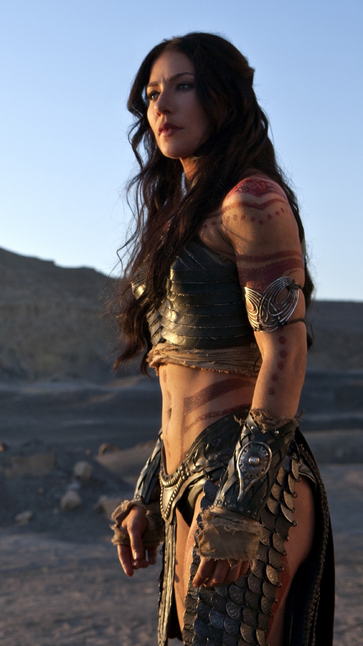 Mujer en Vestido Sin Mangas Marrón de Pie Sobre la Arena Marrón Durante el Día. Wallpaper in 720x1280 Resolution