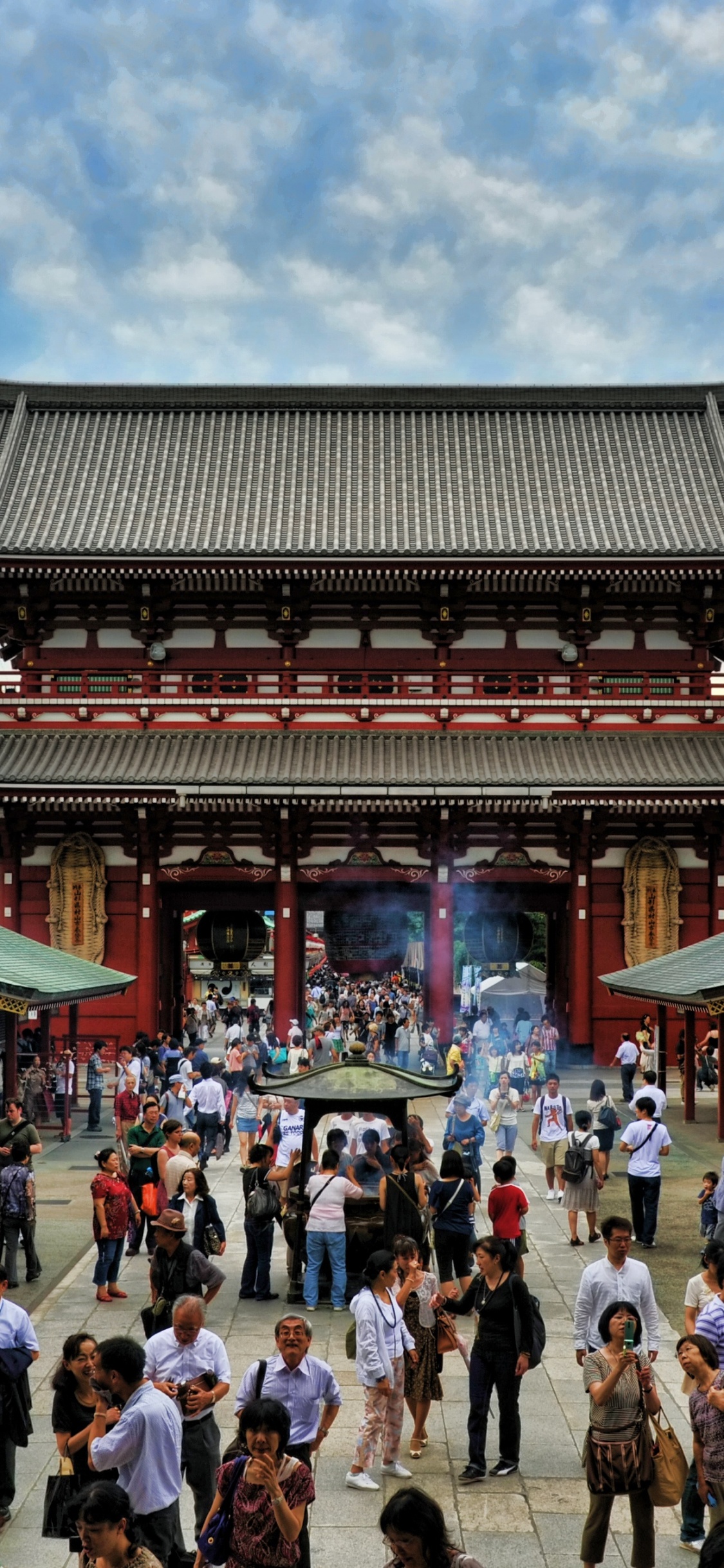 People Walking on Street Near Green and Brown Temple During Daytime. Wallpaper in 1125x2436 Resolution