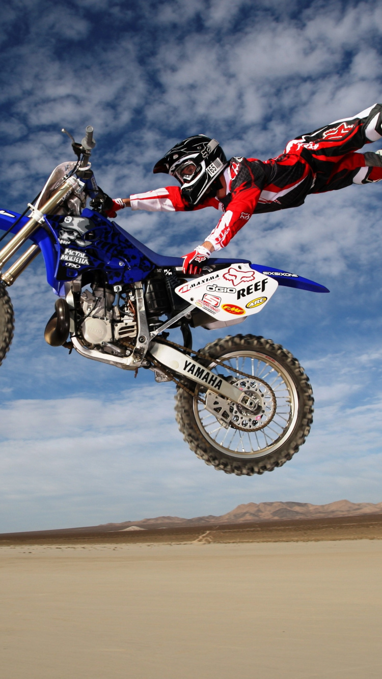 Hombre Montando Motocross Dirt Bike Sobre Arena Marrón Bajo un Cielo Azul Durante el Día. Wallpaper in 750x1334 Resolution