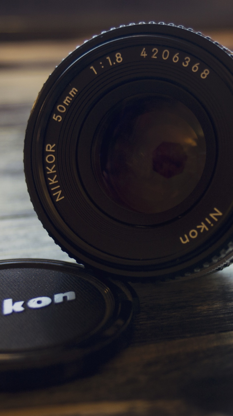 Objectif de L'appareil Photo Nikon Noir Sur Une Table en Bois Marron. Wallpaper in 750x1334 Resolution