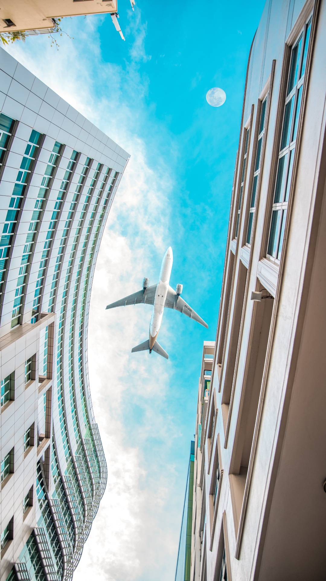 Weißes Flugzeug, Das Tagsüber Über Das Hochhaus Fliegt. Wallpaper in 1080x1920 Resolution