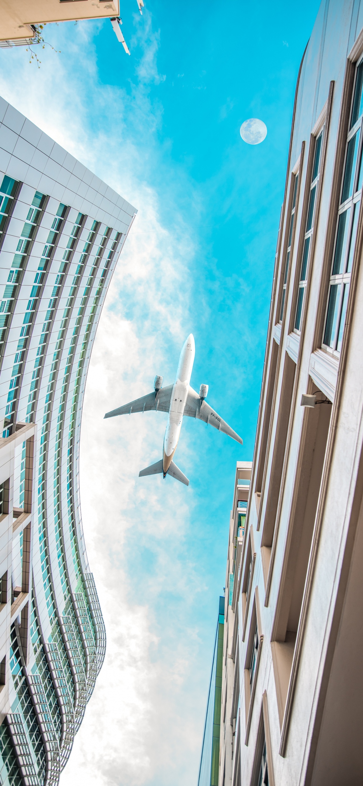 Weißes Flugzeug, Das Tagsüber Über Das Hochhaus Fliegt. Wallpaper in 1242x2688 Resolution