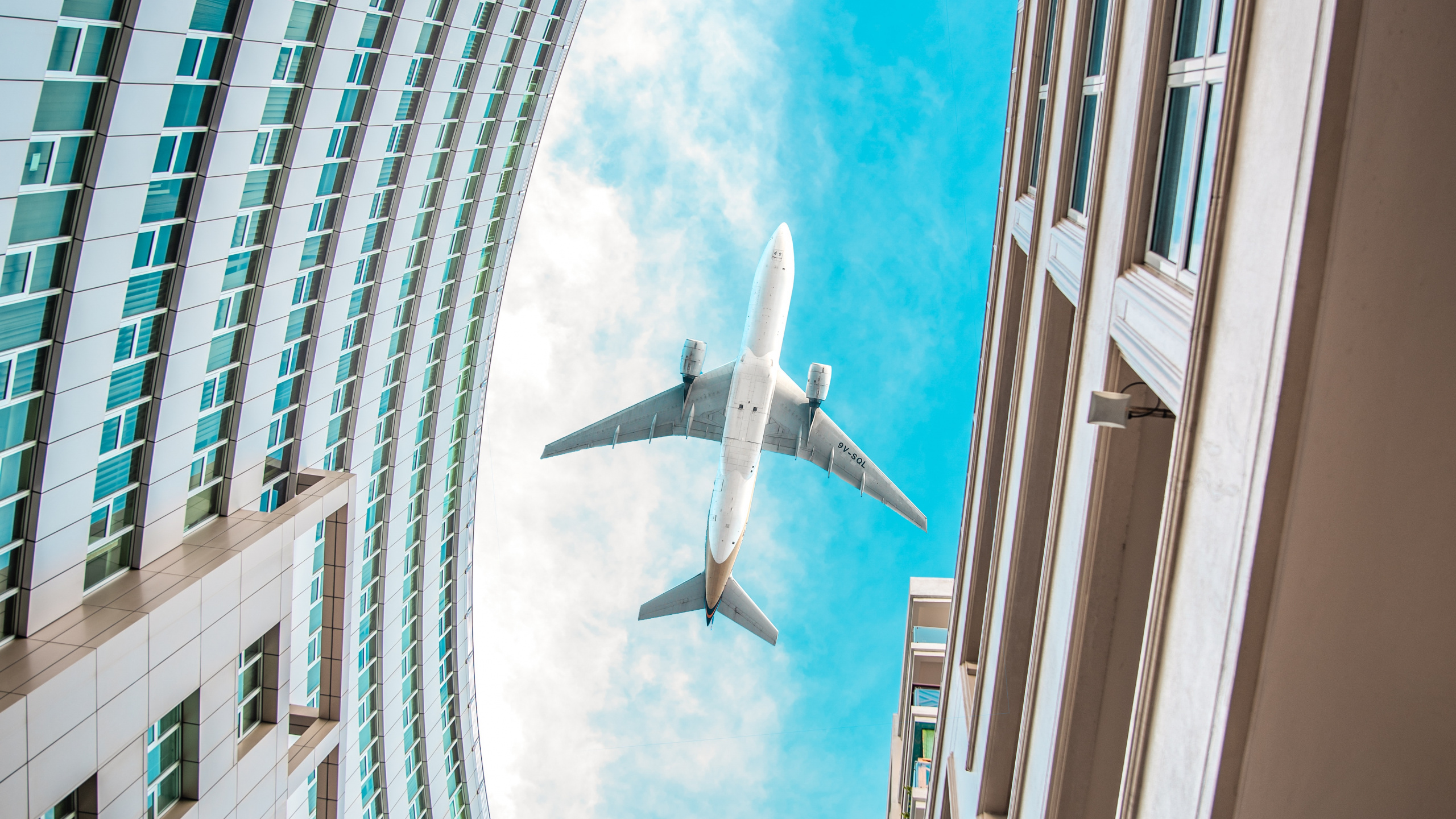 Weißes Flugzeug, Das Tagsüber Über Das Hochhaus Fliegt. Wallpaper in 2560x1440 Resolution